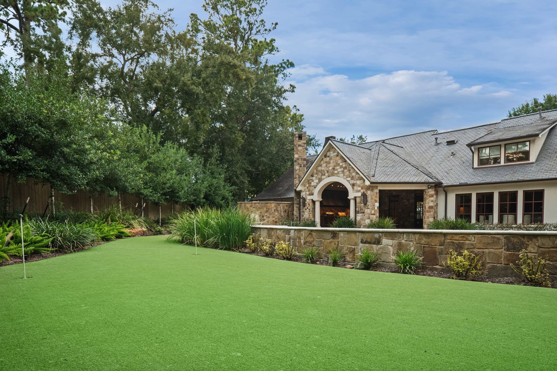 1 Gage Court, Houston, TX 77024 The backyard features an eight-hole putting green with an integrated sand trap, creating a private golf amenity within the fully gated grounds. Mature landscaping surrounds the green while preserving open views back toward the residence and pavilion.