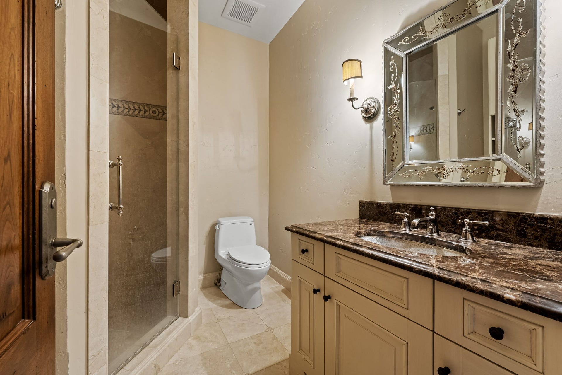 1 Gage Court, Houston, TX 77024 The adjacent hall bath is finished with marble flooring, a furniture-style vanity and marble countertop. A hammered nickel sink, Venetian mirror and stone shower add distinctive custom detailing.