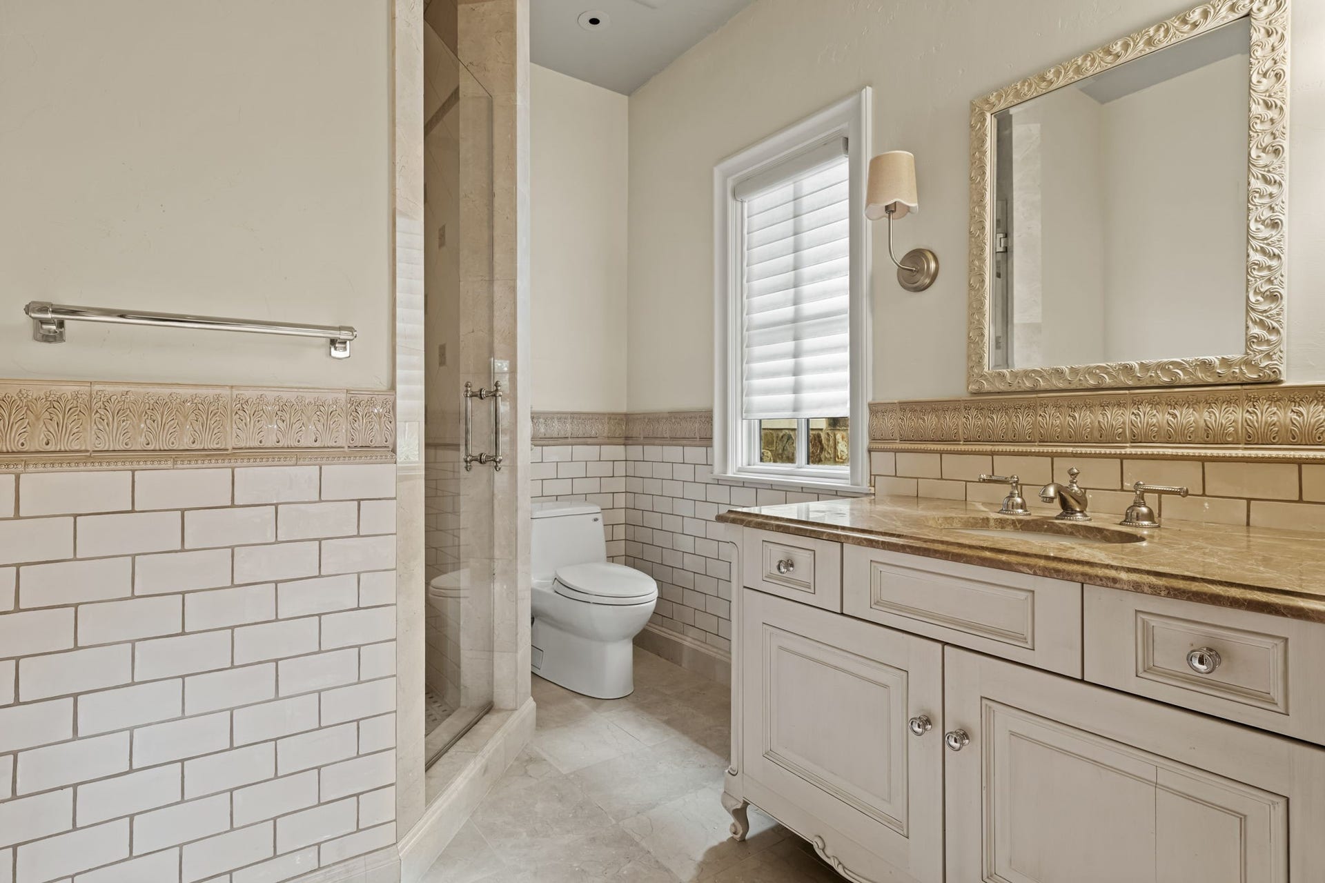 1 Gage Court, Houston, TX 77024 The private en suite bath features marble flooring, glazed subway tile wainscoting and a furniture-style vanity with marble countertop. A window brings natural light into the space while maintaining the homes tailored, traditional finish.