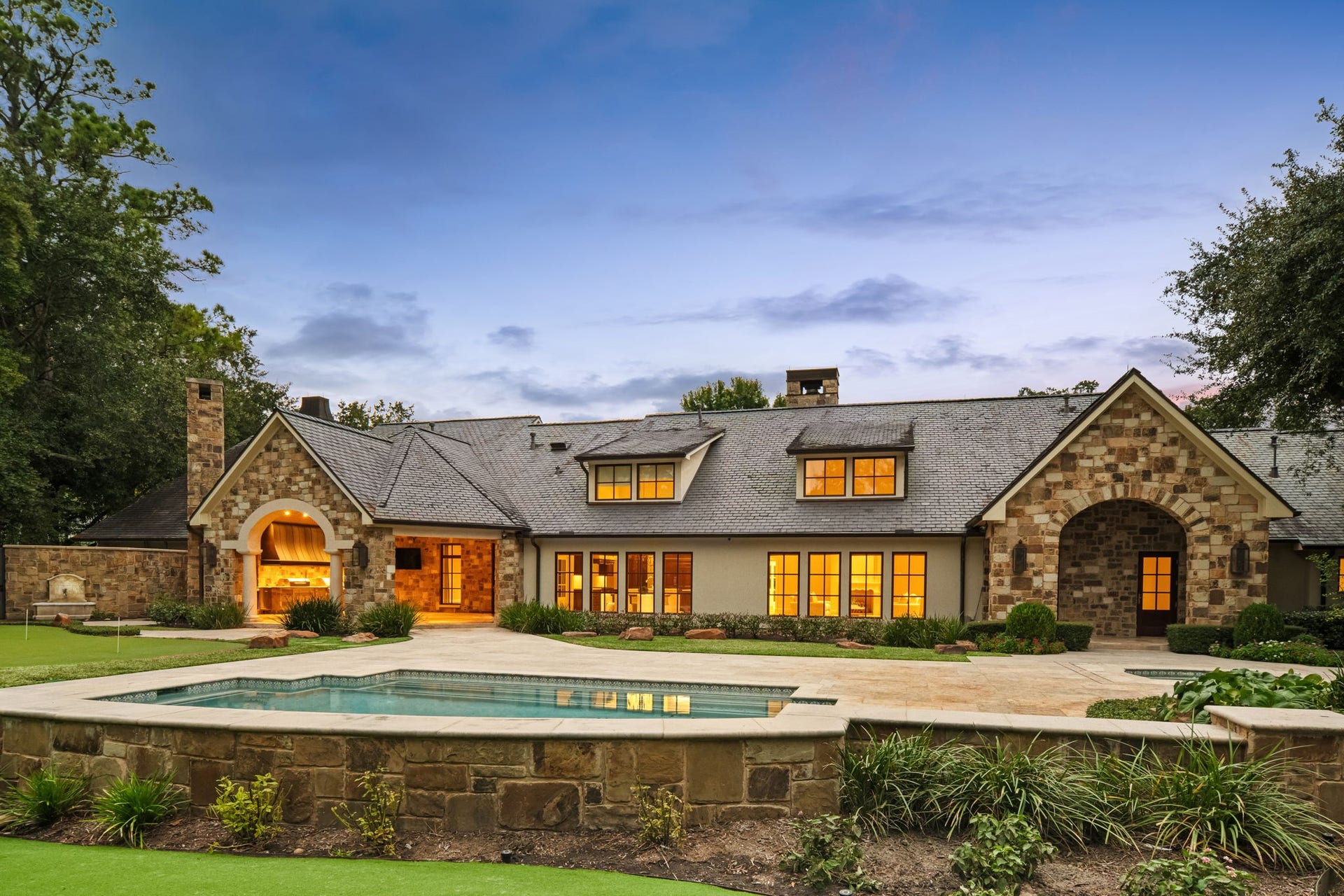 1 Gage Court, Houston, TX 77024 1 Gage Court, the rear elevation showcases the homes timeless architecture beneath a slate roof with copper gutters, overlooking the pool and landscaped grounds. The nearly acre-sized, fully gated estate creates a private resort-style setting in the heart of Memorial.