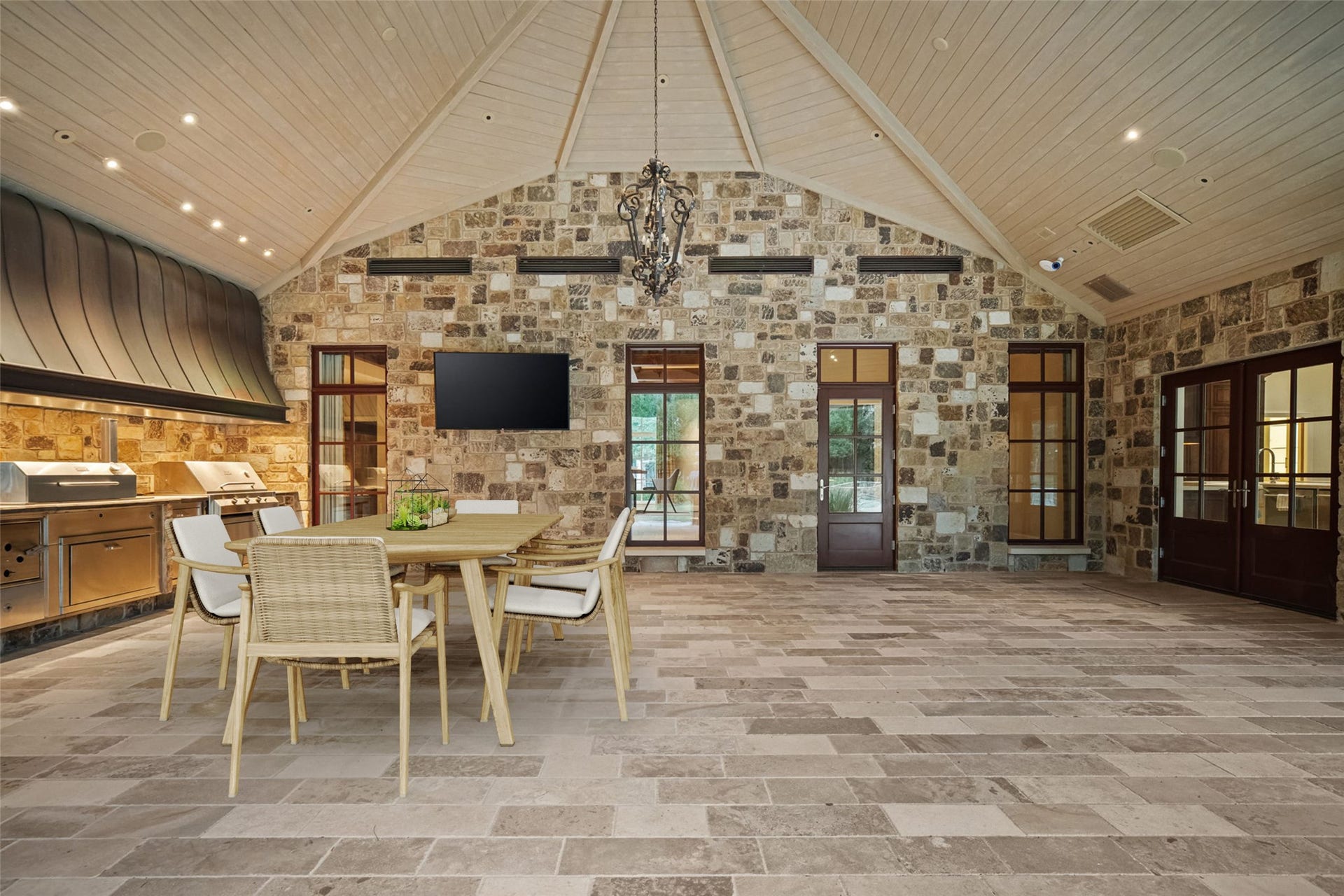 1 Gage Court, Houston, TX 77024 The fully air-conditioned outdoor pavilion is finished with chiseled-edge travertine flooring and an approximately 19-foot vaulted ceiling. A full summer kitchen and generous dining area make the space comfortable for year-round entertaining. (digitally staged)