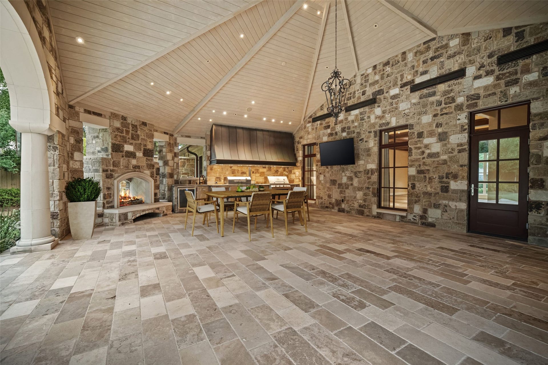 1 Gage Court, Houston, TX 77024 The pavilions dual-sided wood-burning fireplace anchors the space while the adjoining summer kitchen keeps outdoor entertaining fully equipped. A Texas Pit Crafters grill and smoker, sink and beverage refrigerator are integrated into the cooking area. (digitally staged)