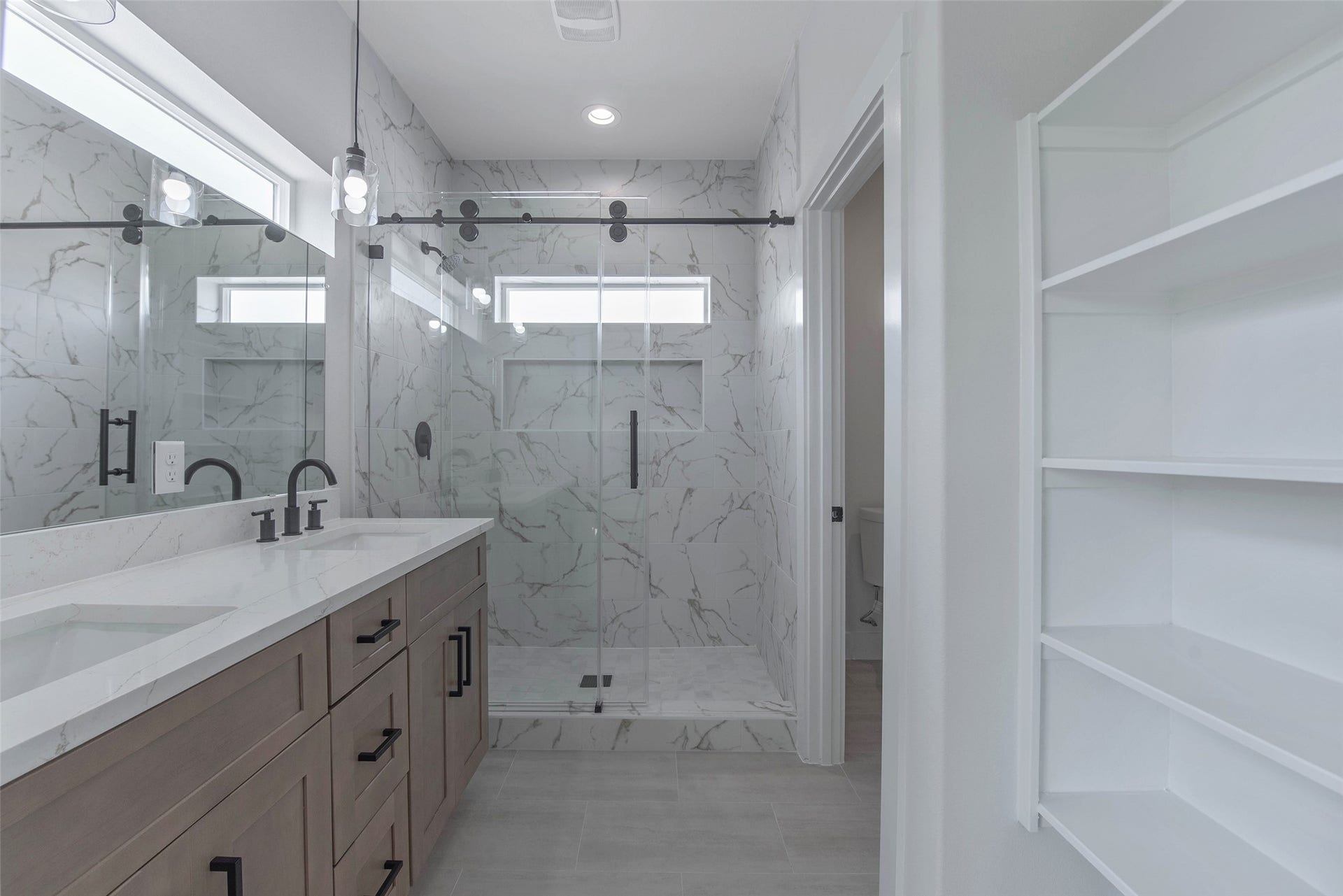 The primary bath offers dual vanities with quartz countertops, a large mirror, a spacious walk-in shower, and ample storage, creating a comfortable and well-appointed retreat.