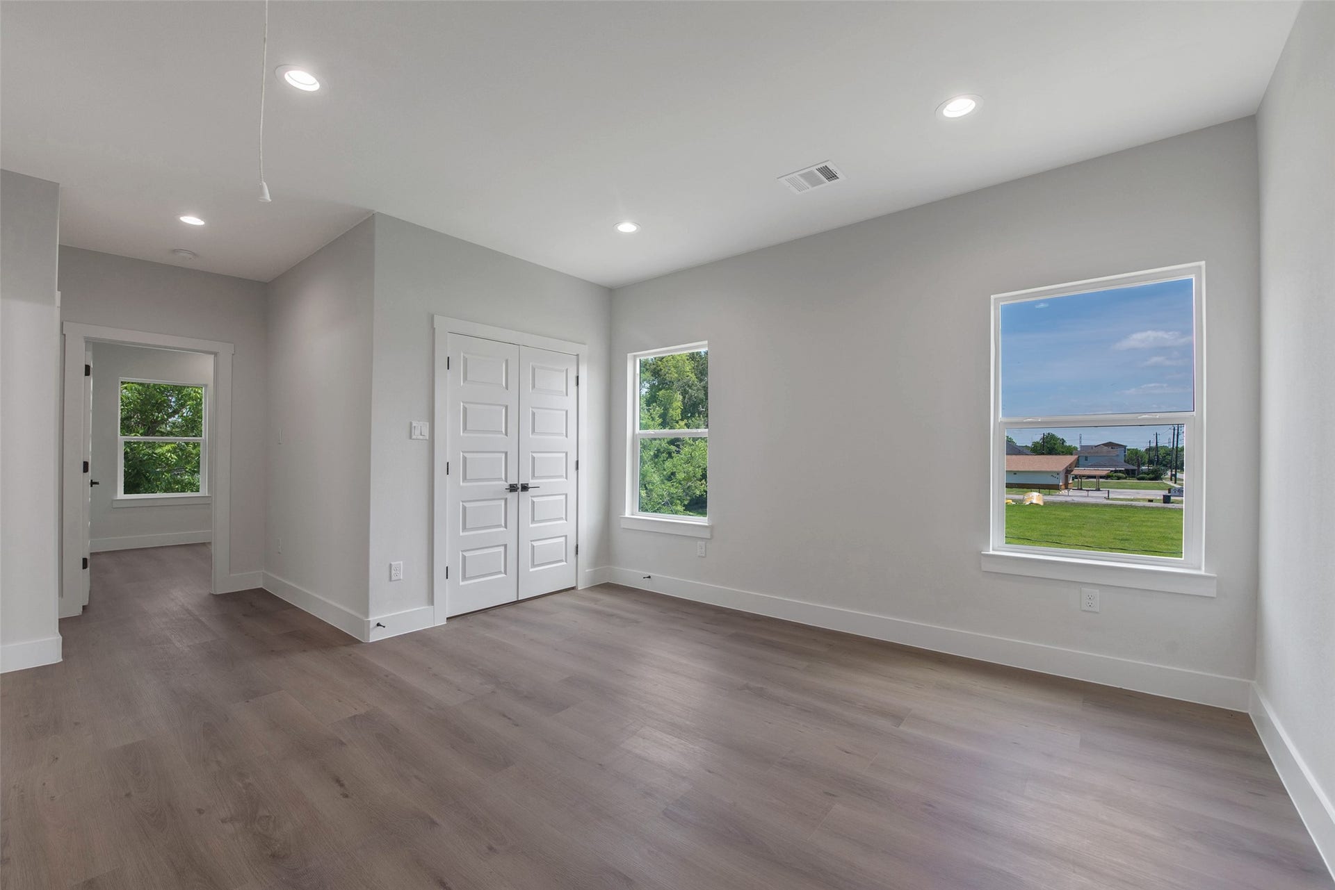 A spacious upstairs flex space, filled with natural light from the windows, offers versatile use for work, play, or relaxation, with bedrooms located just off the space for added convenience and privacy, along with a utility closet for practical storage.