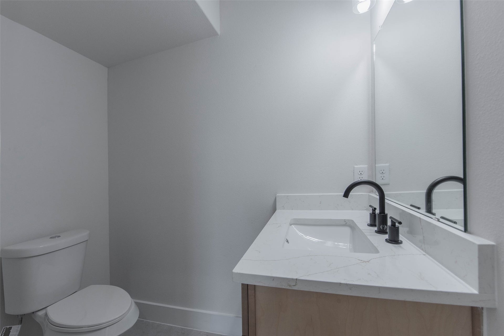 The powder room is conveniently located just off the living room and features quartz countertops and a stylish vanity, offering a bright and functional space.