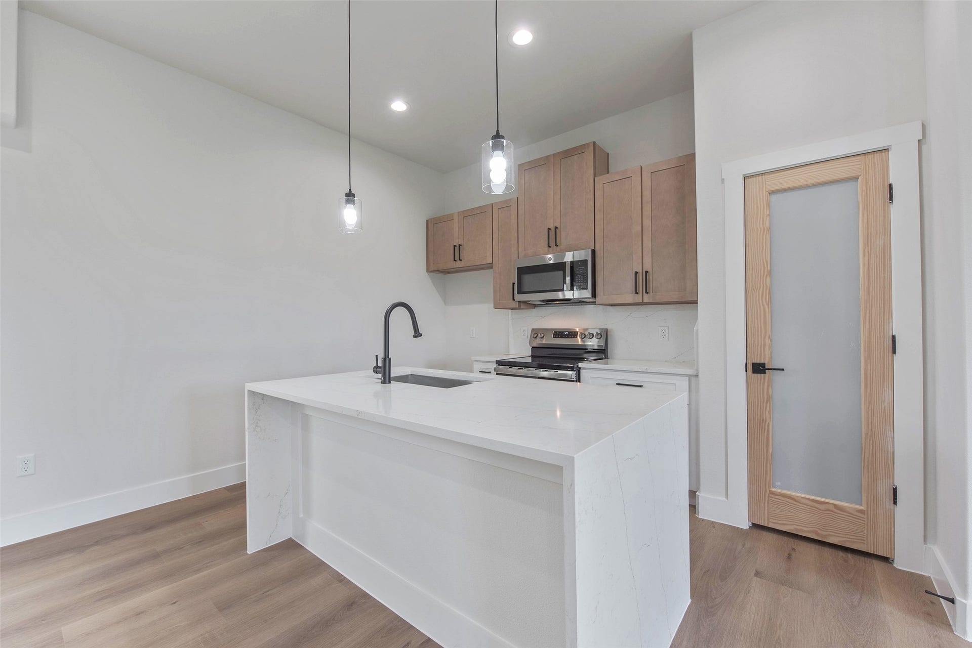 The kitchen features a large island with a farmhouse sink, beautiful cabinetry, a spacious pantry, and sleek stainless steel appliances.