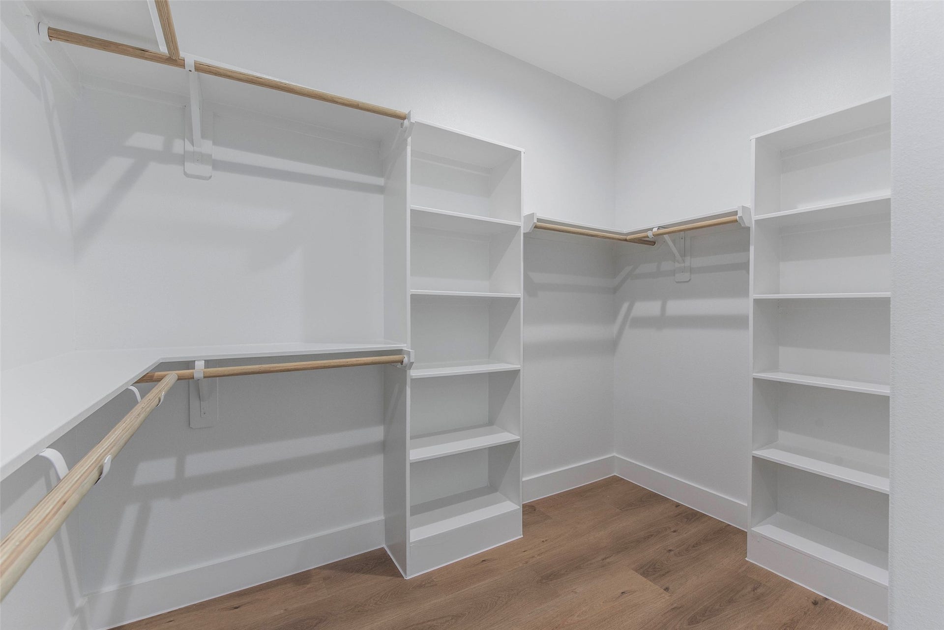 An ample walk-in closet featuring built-in shelving and generous hanging space, thoughtfully designed for organized, effortless storage.