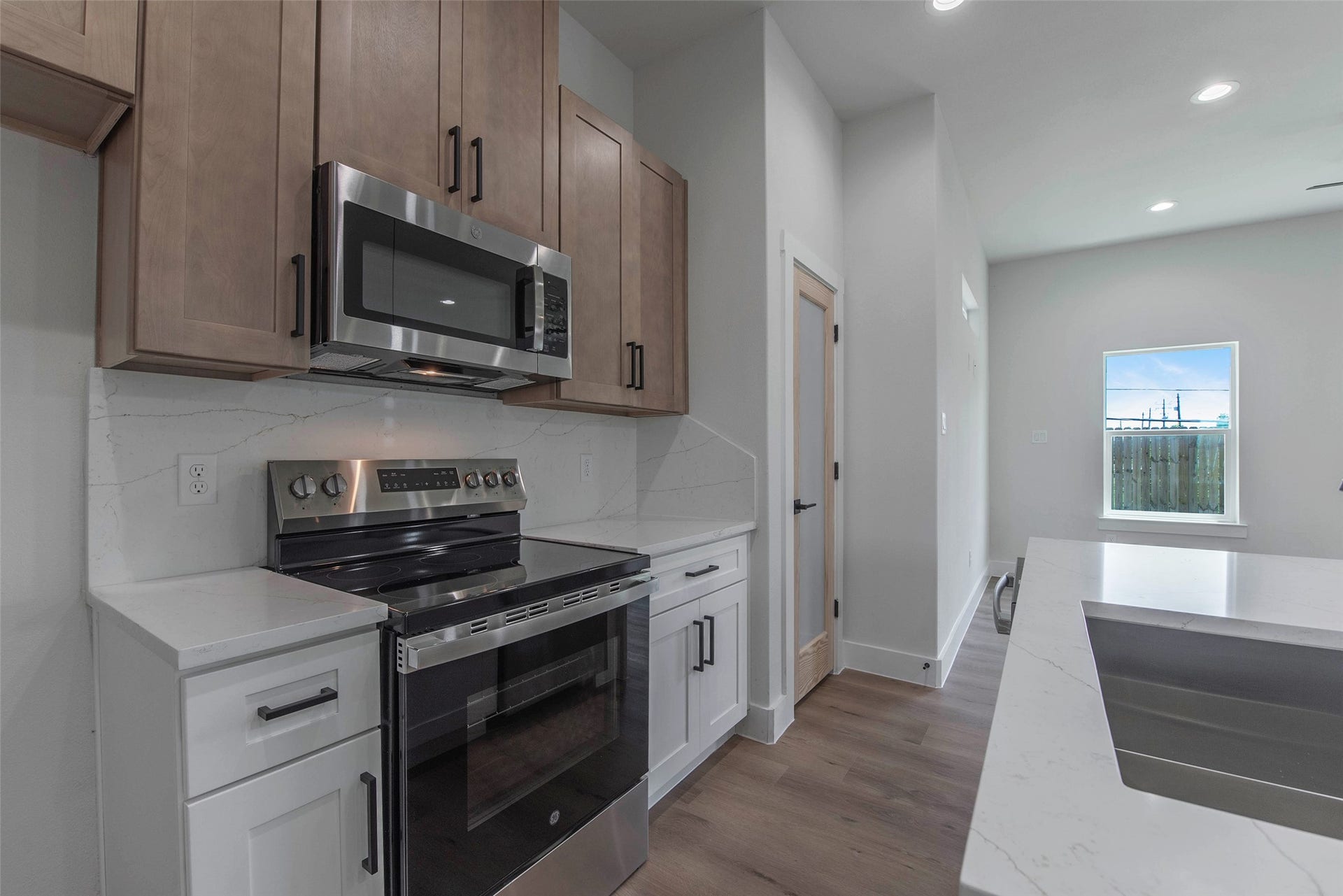 The kitchen is fully equipped with quartz countertops, a cooking range, microwave, and dishwasher, combining style and functionality for everyday living.
