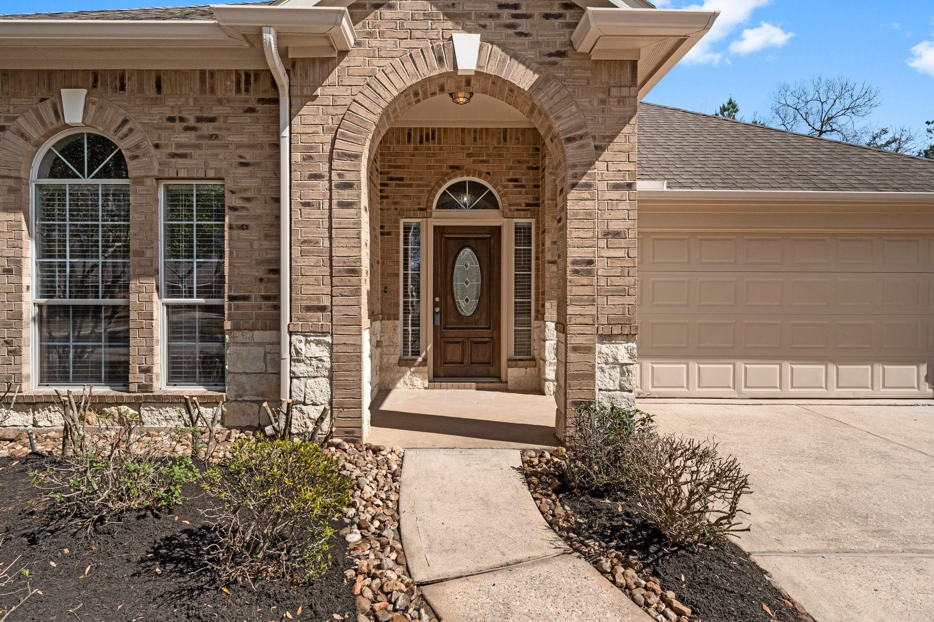 34 Bryce Branch Circle, The Woodlands, TX 77382 Guests will be impressed with the cute front porch boasting arched entry and concrete keystones on the brick work. A gorgeous wood front door with leaded glass is flanked by two skylights and an eyebrow transom above.