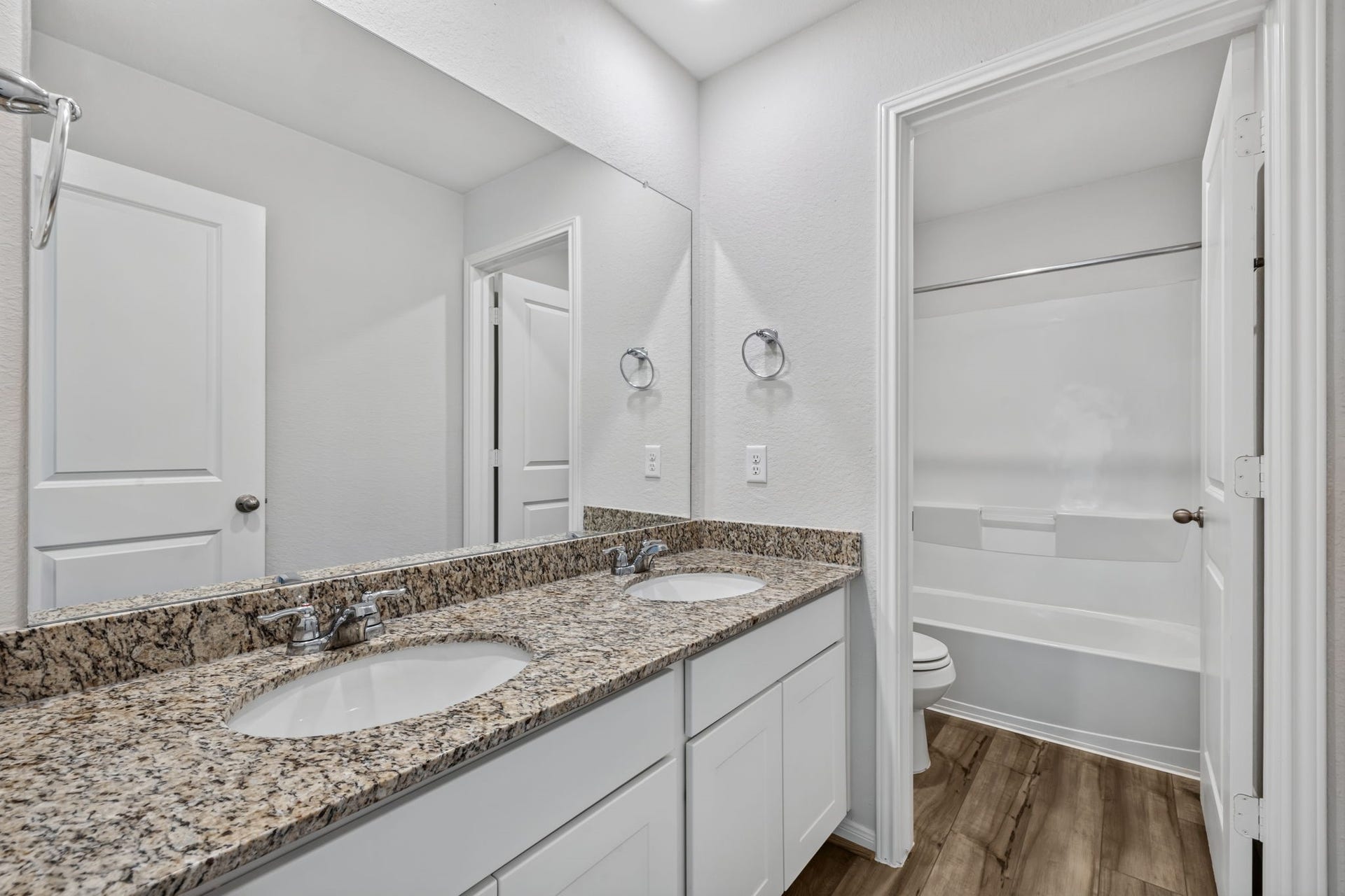 5243 Shallowhurst Lane, Katy, TX 77449 SECONDARY BATHROOM II - The secondary bath has a granite double vanity with white shaker cabinets, plus a separate tub/shower and toilet area behind a door.