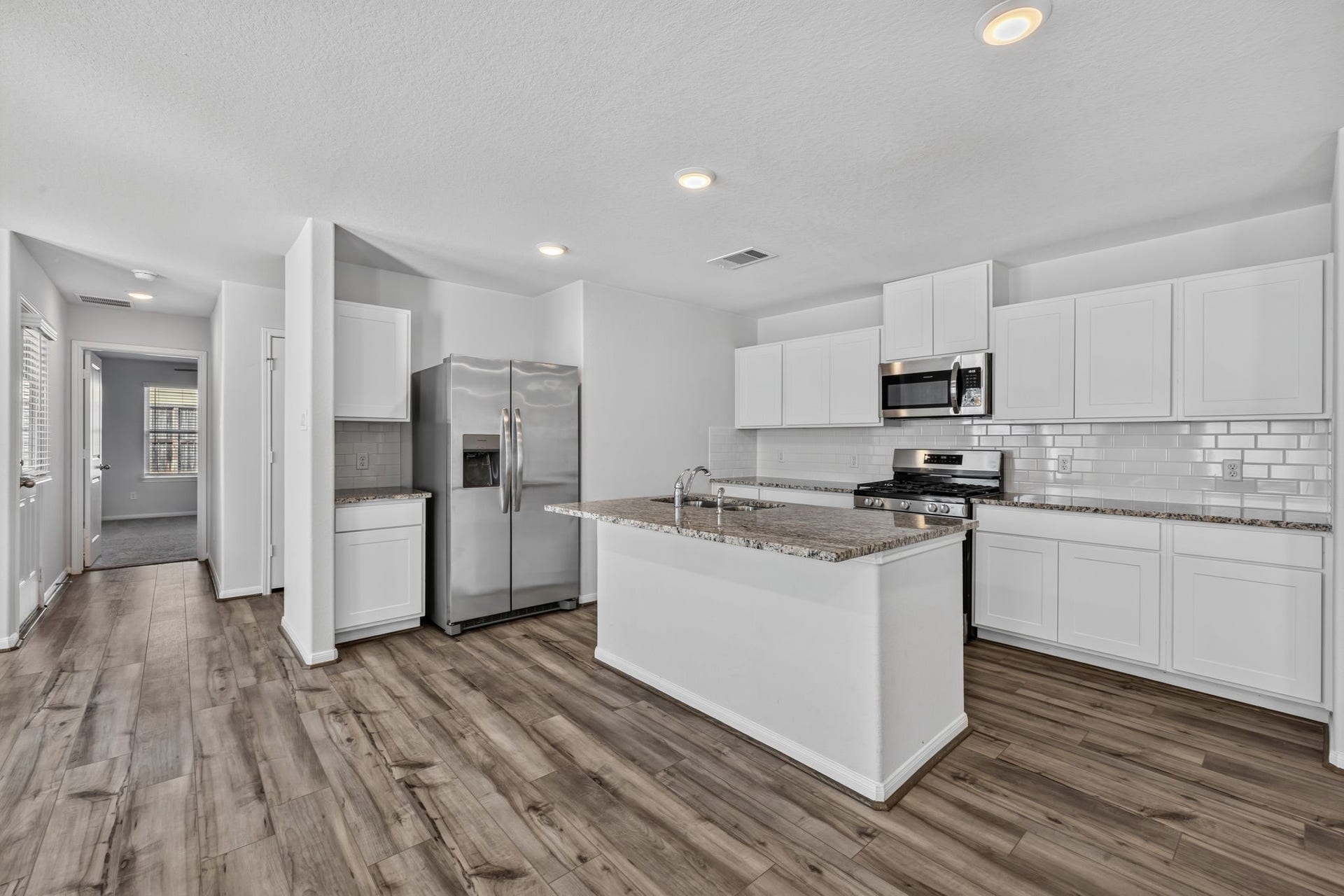 5243 Shallowhurst Lane, Katy, TX 77449 KITCHEN - The kitchen has white shaker cabinets, granite countertops, subway tile backsplash, and a stainless steel appliance package with a side-by-side refrigerator.