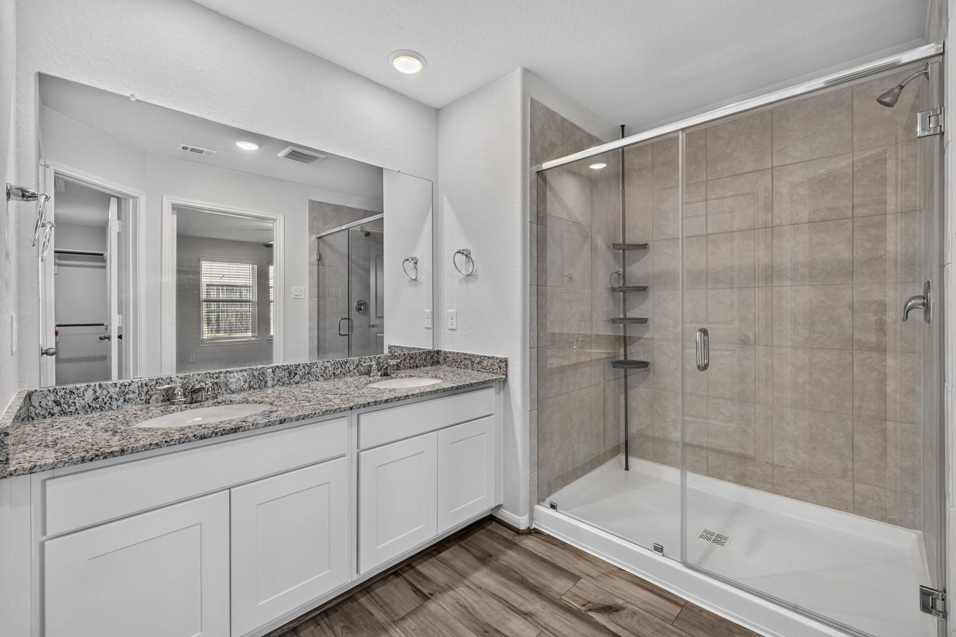 5243 Shallowhurst Lane, Katy, TX 77449 PRIMARY BATHROOM - The primary bath has a granite double vanity, a large walk-in shower with tile surround and glass enclosure, and a view into the walk-in closet.