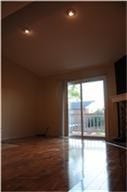 6001 Reims Road, #1202, Houston, TX 77036 This photo shows a room with high ceilings and recessed lighting, featuring hardwood floors and a sliding glass door leading to an outdoor space. There's also a fireplace, adding a cozy touch.