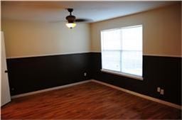 6001 Reims Road, #1202, Houston, TX 77036 This room features hardwood flooring, a ceiling fan, and a large window. The walls are two-toned with a darker shade on the lower half, creating a stylish contrast.
