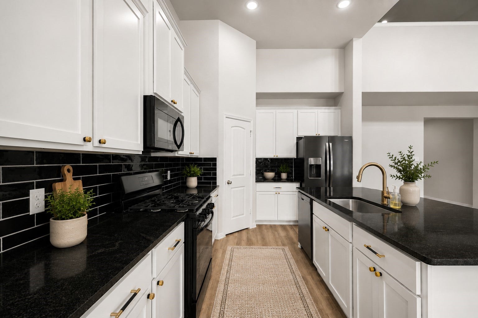 13432 Maverick Trail Road, Conroe, TX 77303 Sleek modern kitchen featuring white cabinetry, black countertops, and a stylish subway tile backsplash, complemented by stainless steel appliances and brass fixtures.