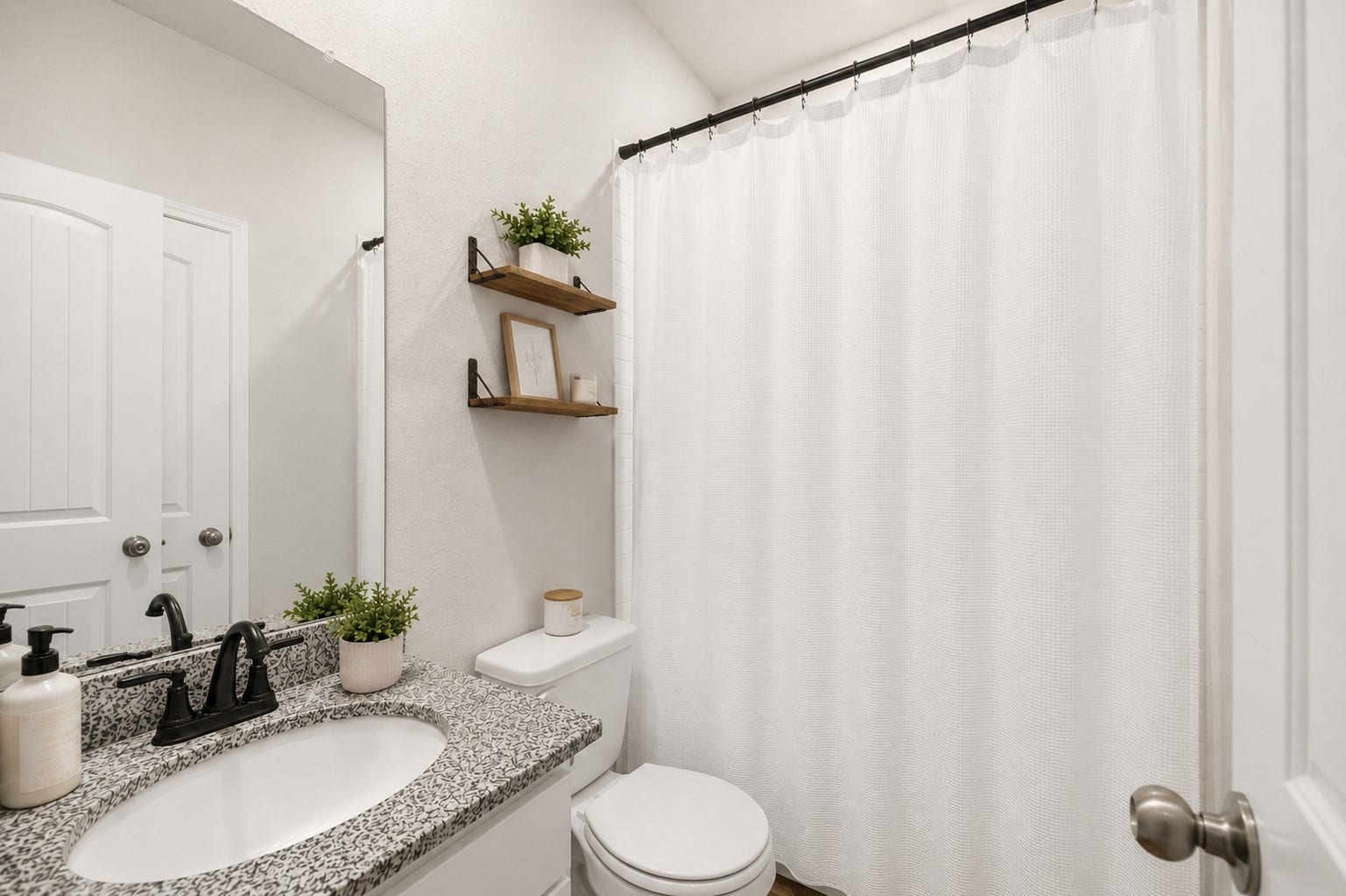 13432 Maverick Trail Road, Conroe, TX 77303 Charming 1st floor full bathroom featuring a sleek granite countertop, modern fixtures, and stylish floating shelves