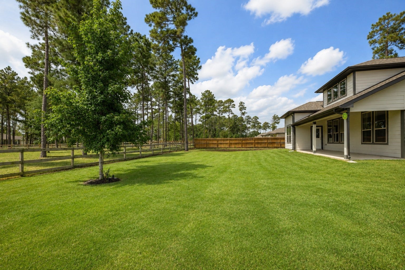 13432 Maverick Trail Road, Conroe, TX 77303 Expansive backyard with lush green lawn, mature trees, and a charming fence, offering ample space for outdoor activities and relaxation.