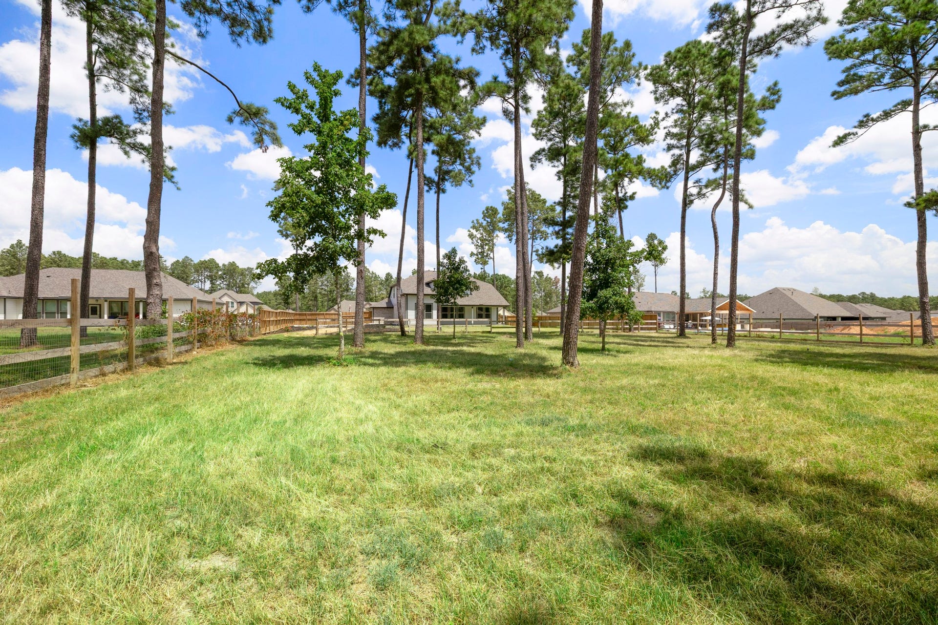 13432 Maverick Trail Road, Conroe, TX 77303 Expansive backyard with lush grass and tall trees, surrounded by a charming wooden fence, offering privacy and a serene setting.