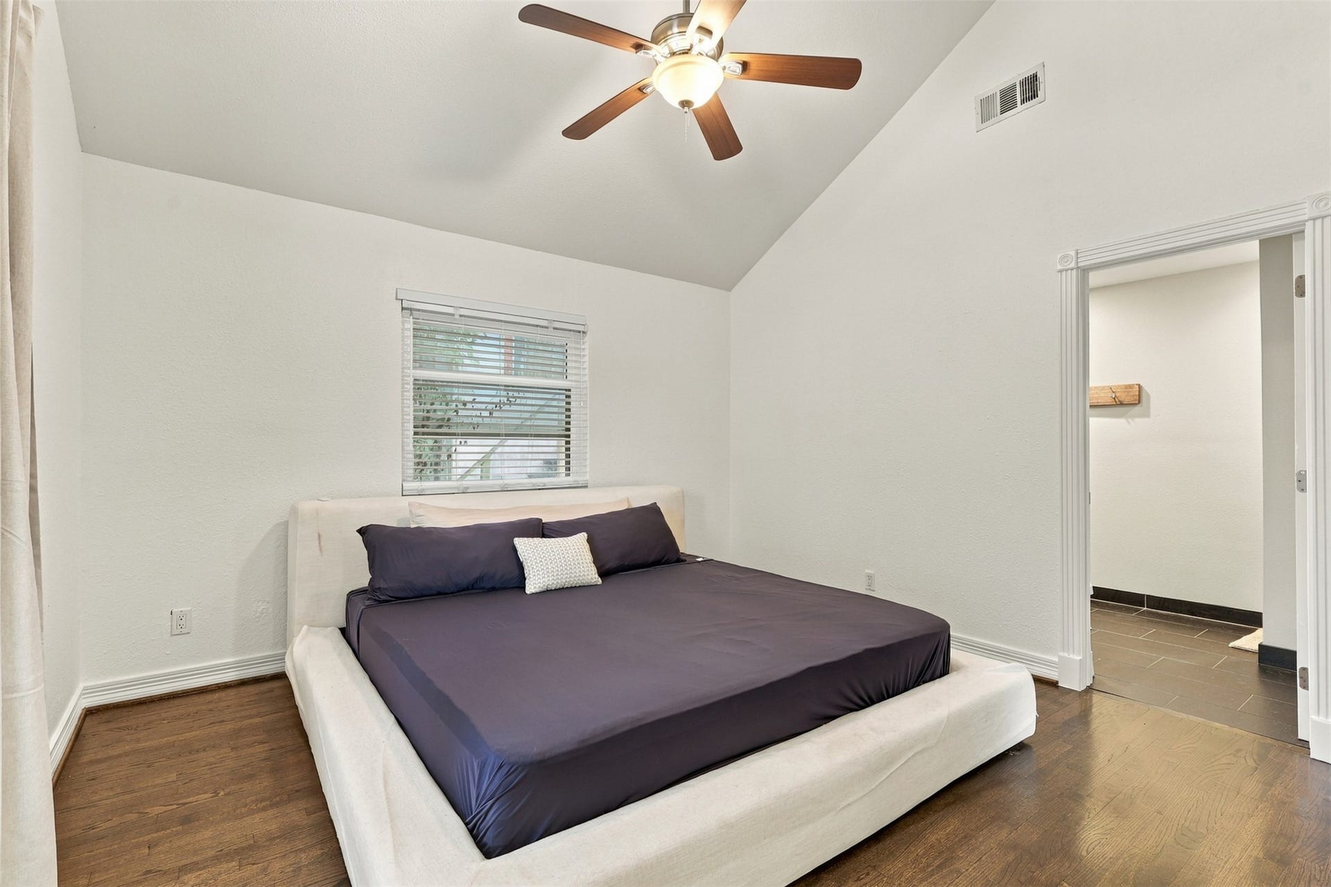 5410 Kiam Street, Houston, TX 77007 Spacious bedroom with vaulted ceiling, elegant ceiling fan, and rich hardwood floors, offering a serene retreat.
