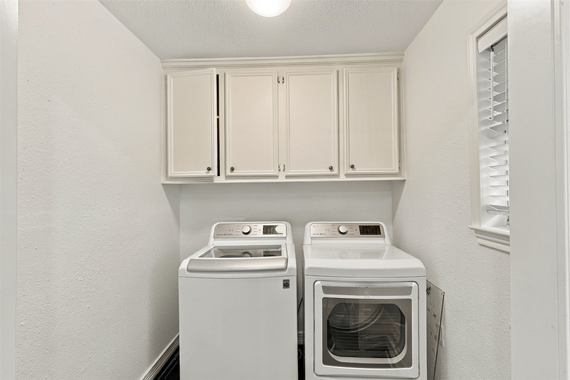 5410 Kiam Street, Houston, TX 77007 Bright and functional laundry room featuring modern washer and dryer, ample storage with overhead cabinetry, and a convenient window for natural light.