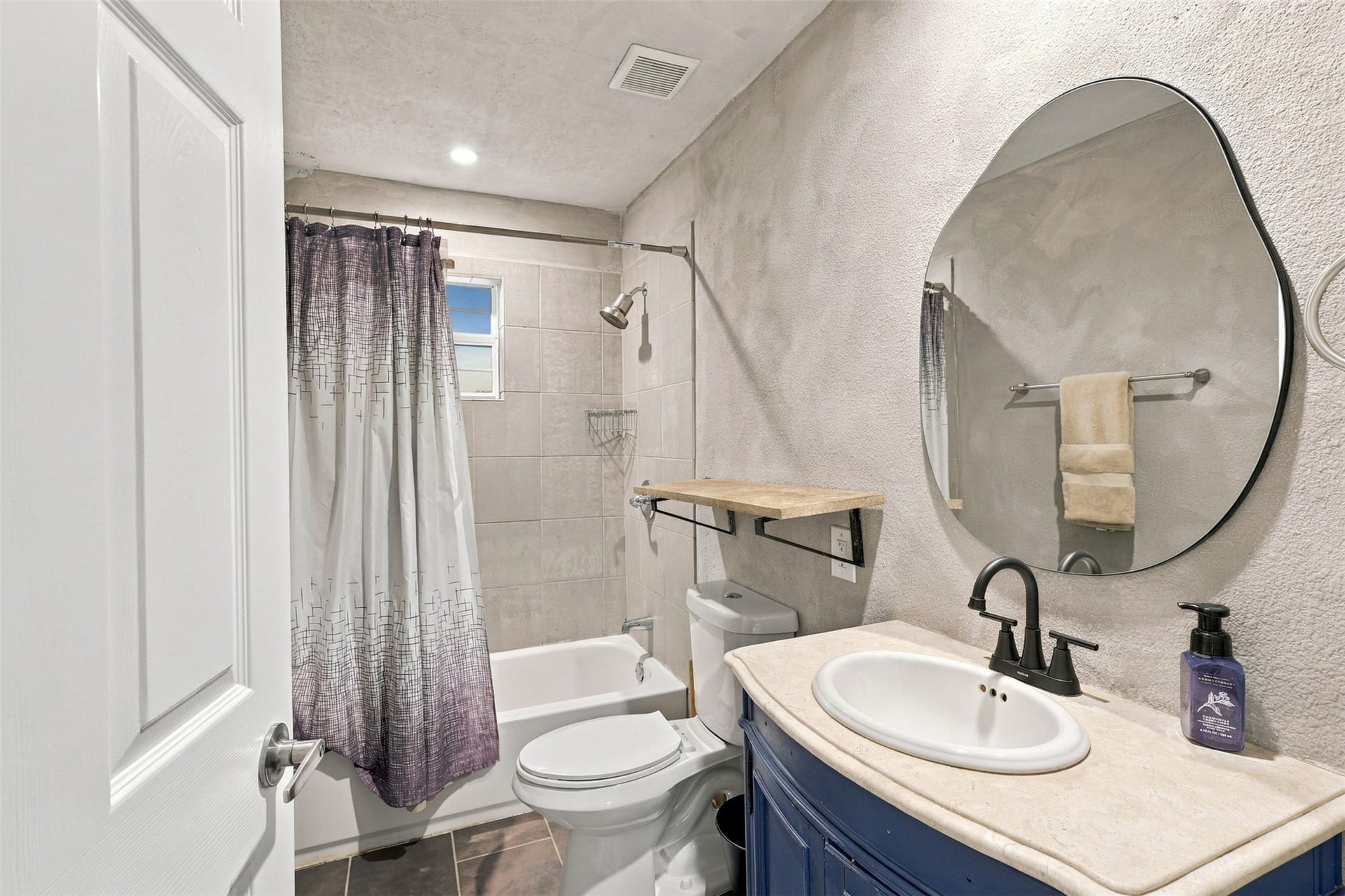 5410 Kiam Street, Houston, TX 77007 Charming bathroom featuring a sleek oval mirror, modern fixtures, and a cozy tub with shower.
