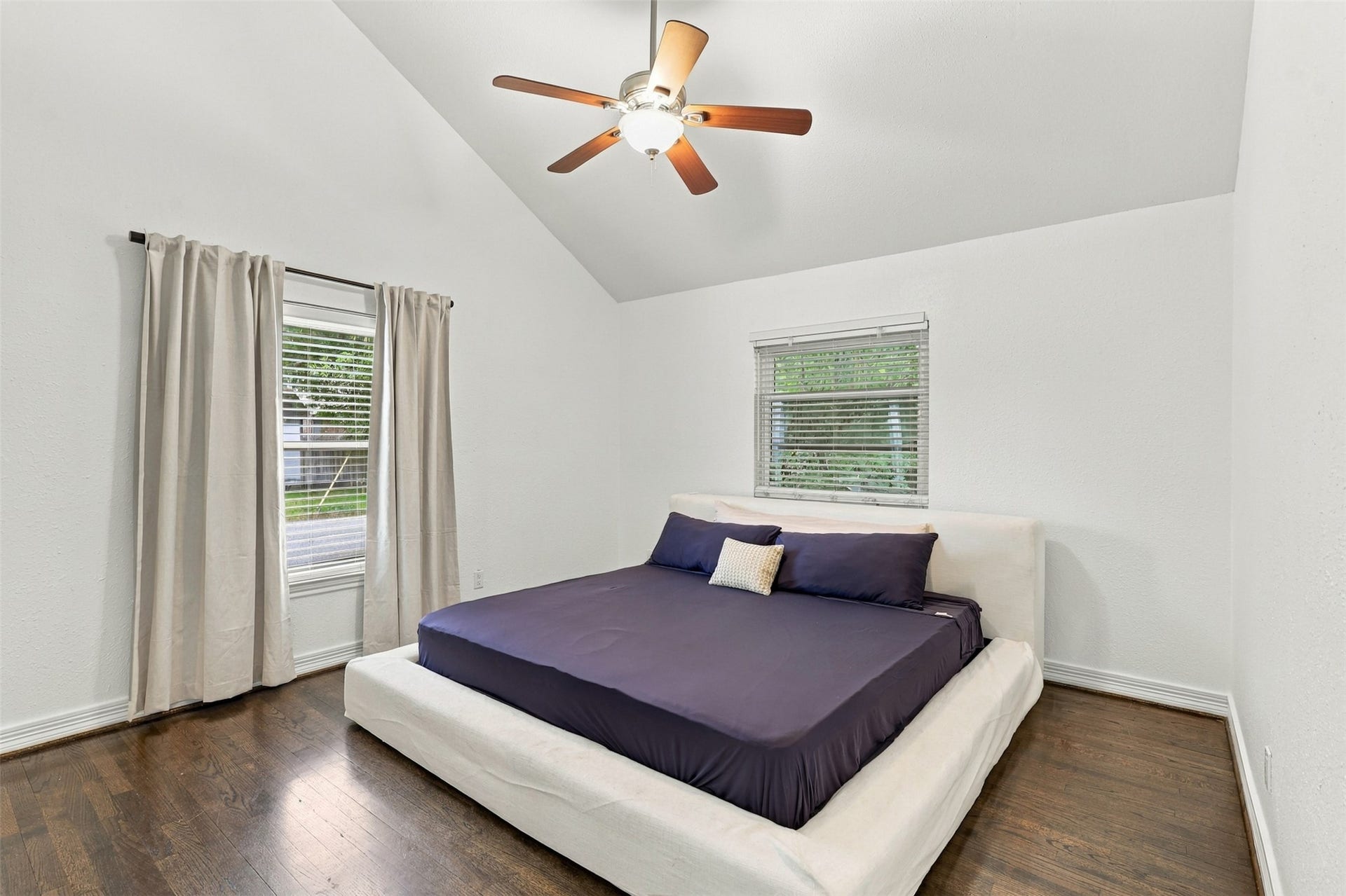 5410 Kiam Street, Houston, TX 77007 Spacious bedroom with vaulted ceilings, featuring a modern ceiling fan and large windows for ample natural light.