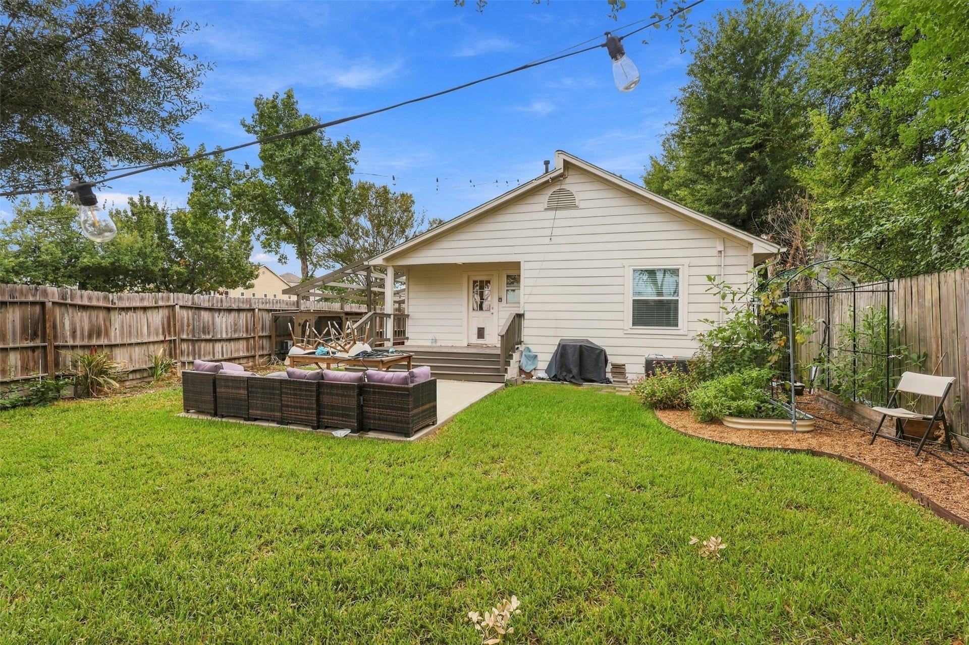5410 Kiam Street, Houston, TX 77007 Charming backyard oasis featuring a cozy patio area with comfortable seating, surrounded by lush greenery and a privacy fence, perfect for relaxation and outdoor gatherings.