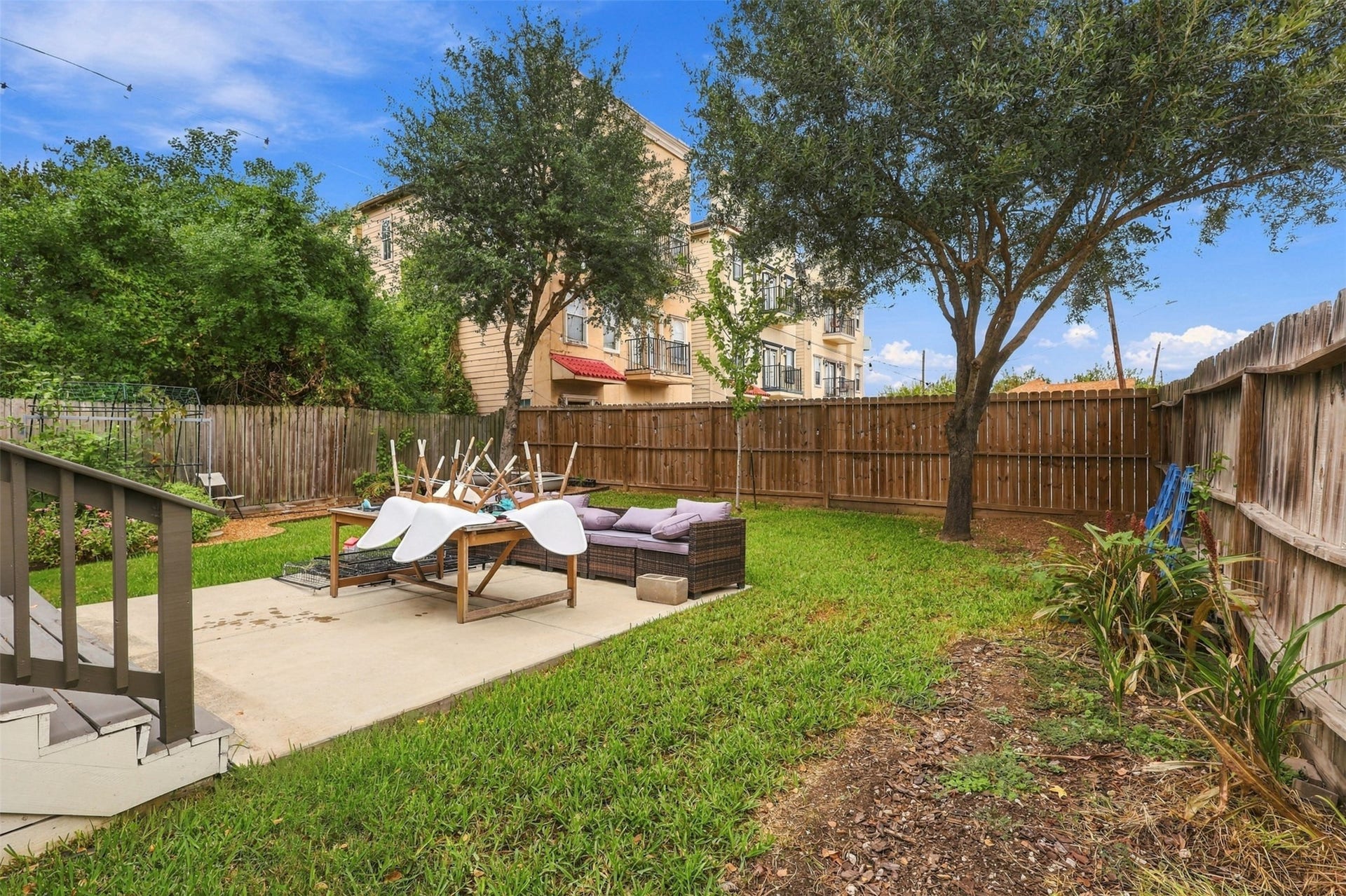 5410 Kiam Street, Houston, TX 77007 Charming backyard with lush greenery, a cozy patio area, and mature trees, perfect for outdoor relaxation and entertainment.
