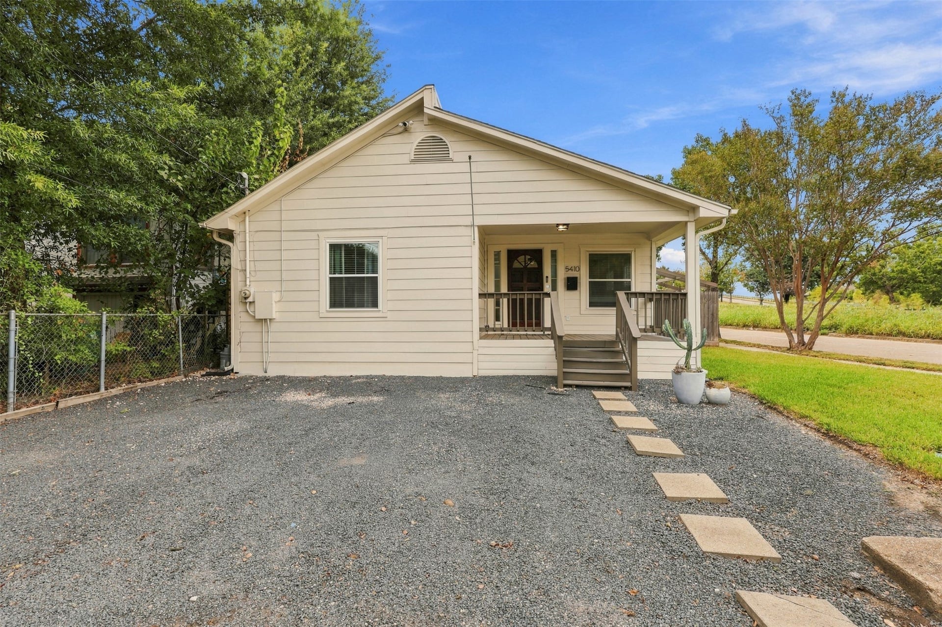 5410 Kiam Street, Houston, TX 77007 Charming single-story home with a welcoming front porch, framed by lush greenery and a spacious driveway, perfect for easy access and outdoor relaxation.