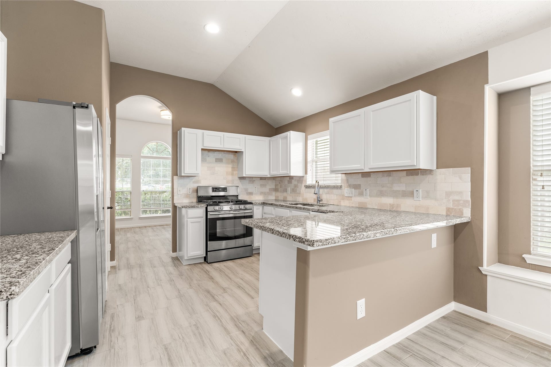 17042 Midnight Sun Lane, Richmond, TX 77407 Beautifully updated kitchen featuring white cabinetry, granite countertops, and a modern stone backsplash.