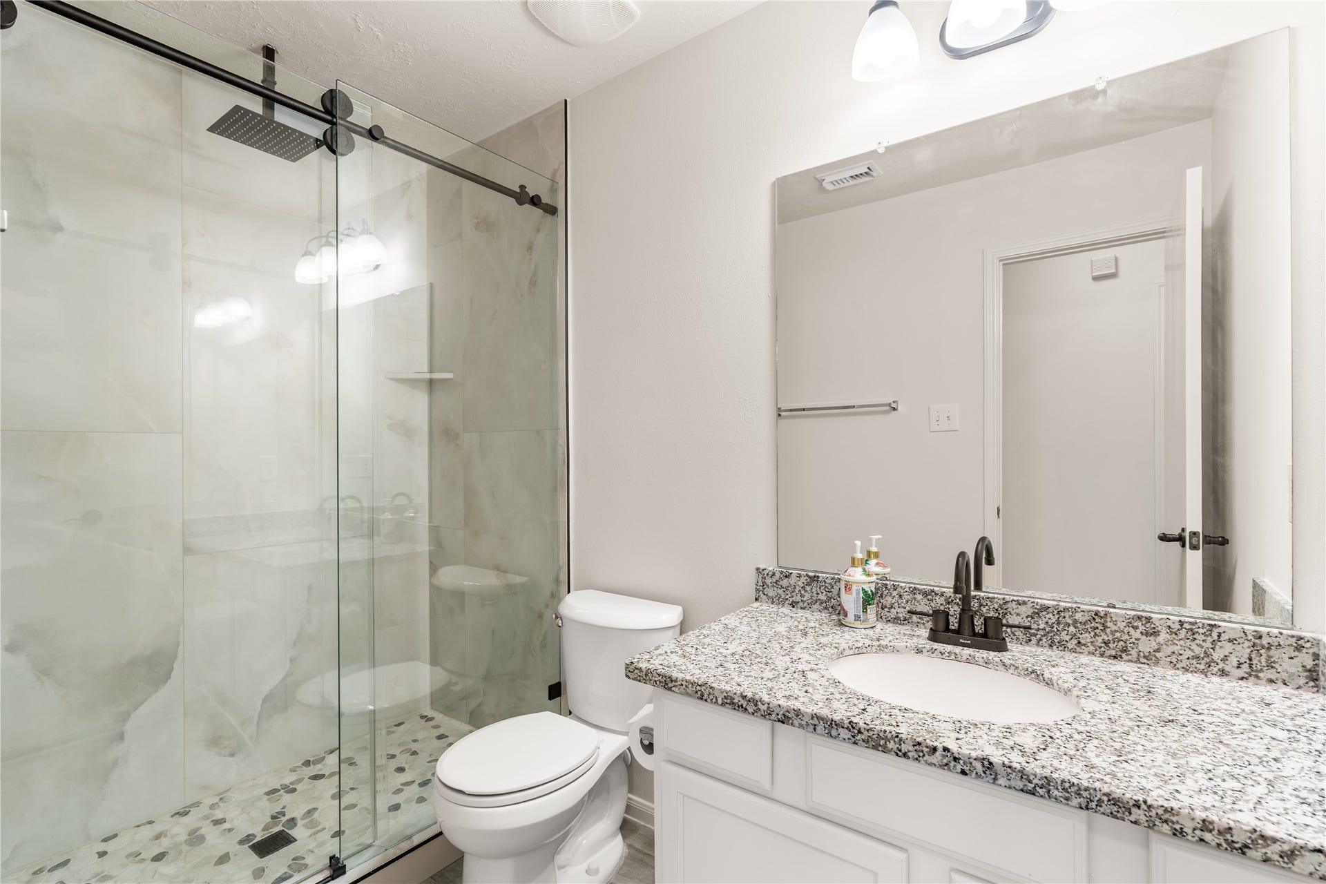 17042 Midnight Sun Lane, Richmond, TX 77407 Updated secondary bathroom featuring granite countertops, modern fixtures, and a frameless glass shower.