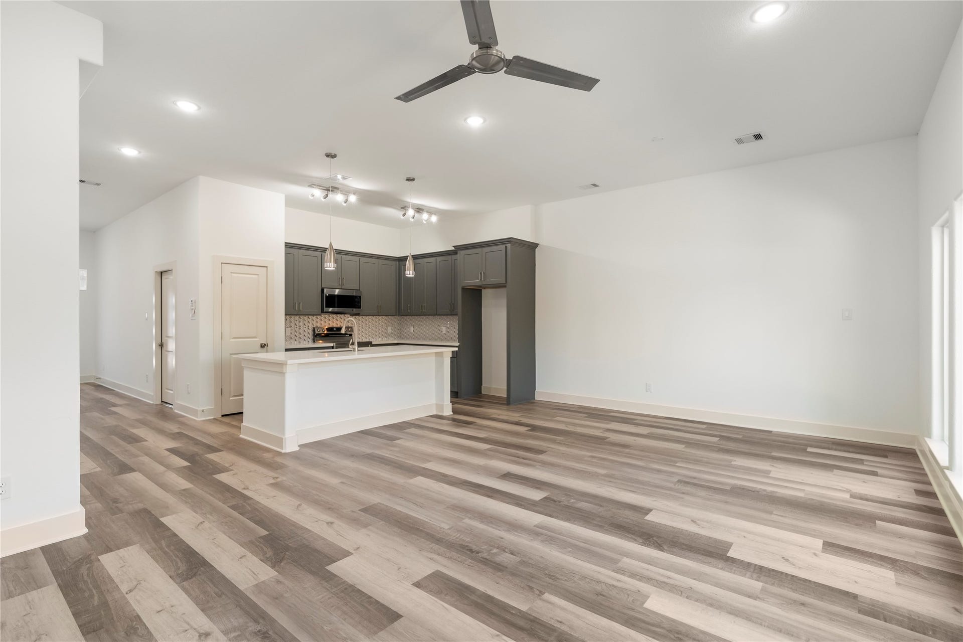 5629 Malmedy Road, Houston, TX 77033 Spacious open-concept living area featuring sleek hardwood floors, a modern kitchen with a large island, pendant lighting, and stylish gray cabinetry, perfect for entertaining and everyday living.