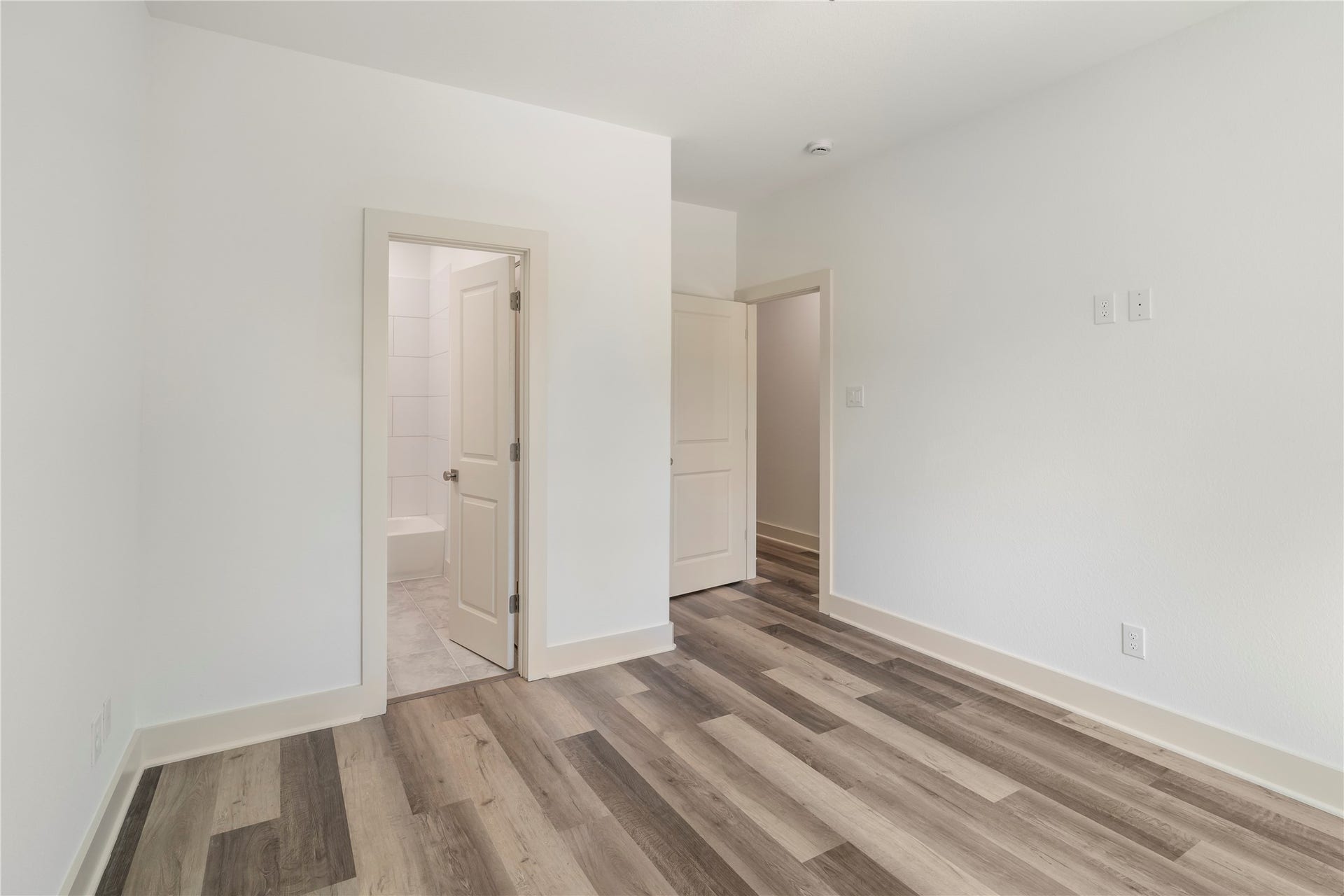 5629 Malmedy Road, Houston, TX 77033 Bright and inviting room with sleek wood flooring and neutral walls, featuring convenient access to an en-suite bathroom.