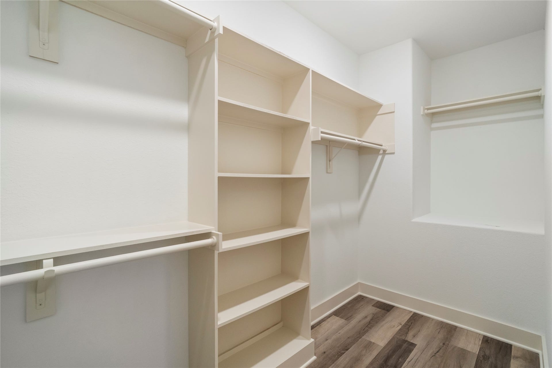 5629 Malmedy Road, Houston, TX 77033 Spacious walk-in closet featuring ample shelving and hanging space, complemented by stylish wood flooring.