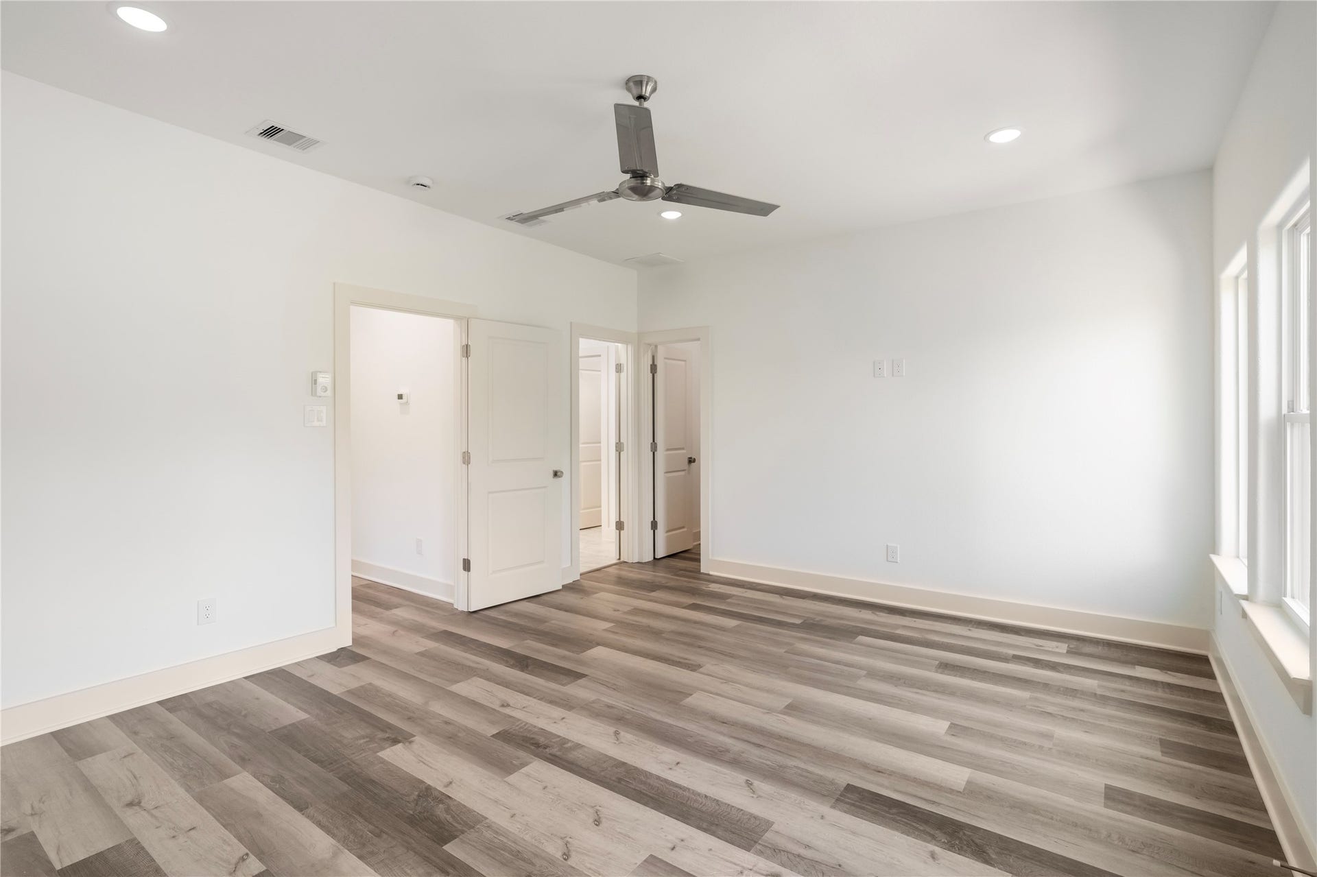 5629 Malmedy Road, Houston, TX 77033 Spacious room with elegant wood-look flooring, abundant natural light, and a modern ceiling fan, offering comfort and style.