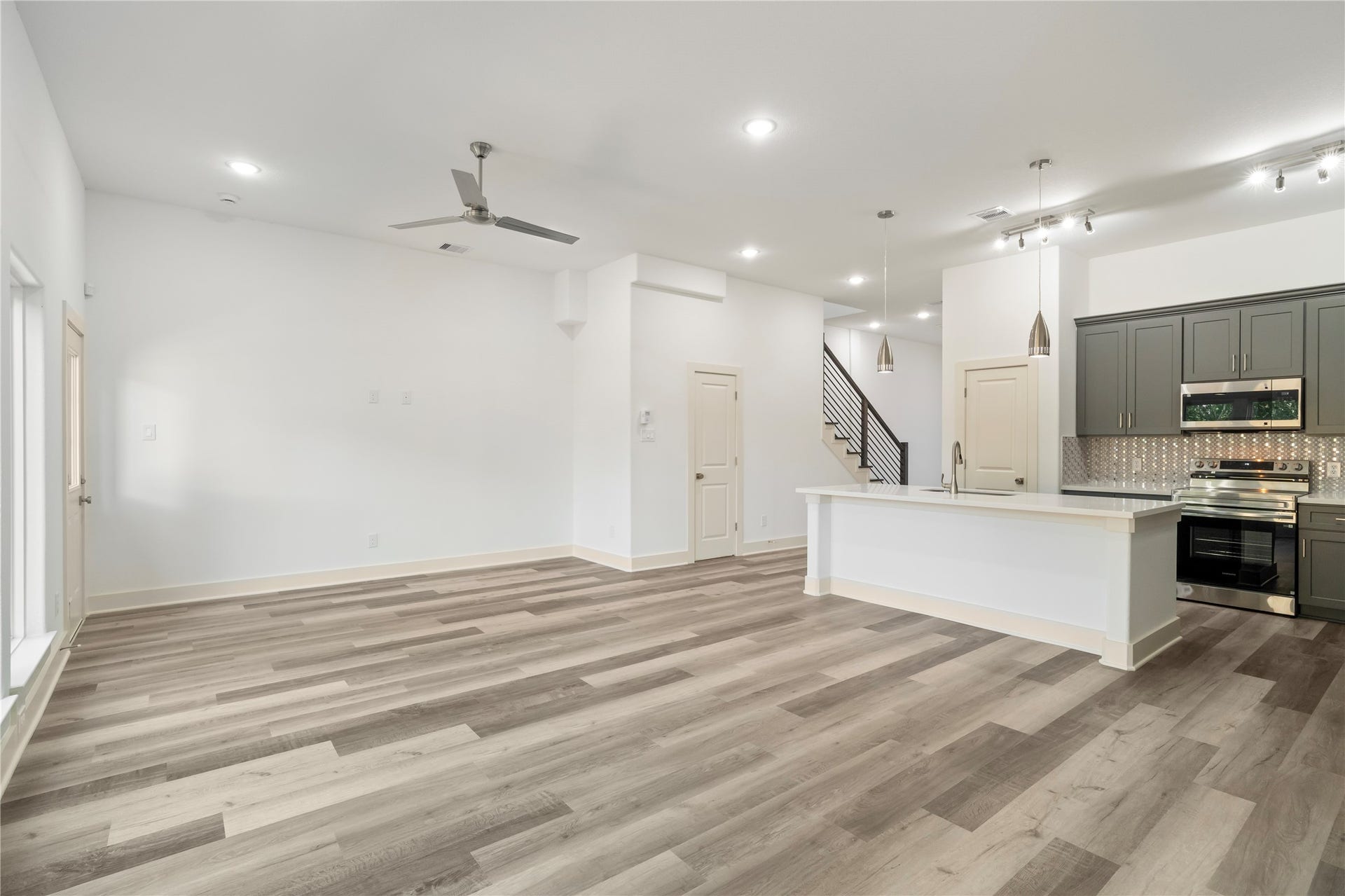 5629 Malmedy Road, Houston, TX 77033 Bright and spacious open-concept living area features sleek wood flooring and a modern kitchen with stainless steel appliances, a large island, and elegant cabinetry.
