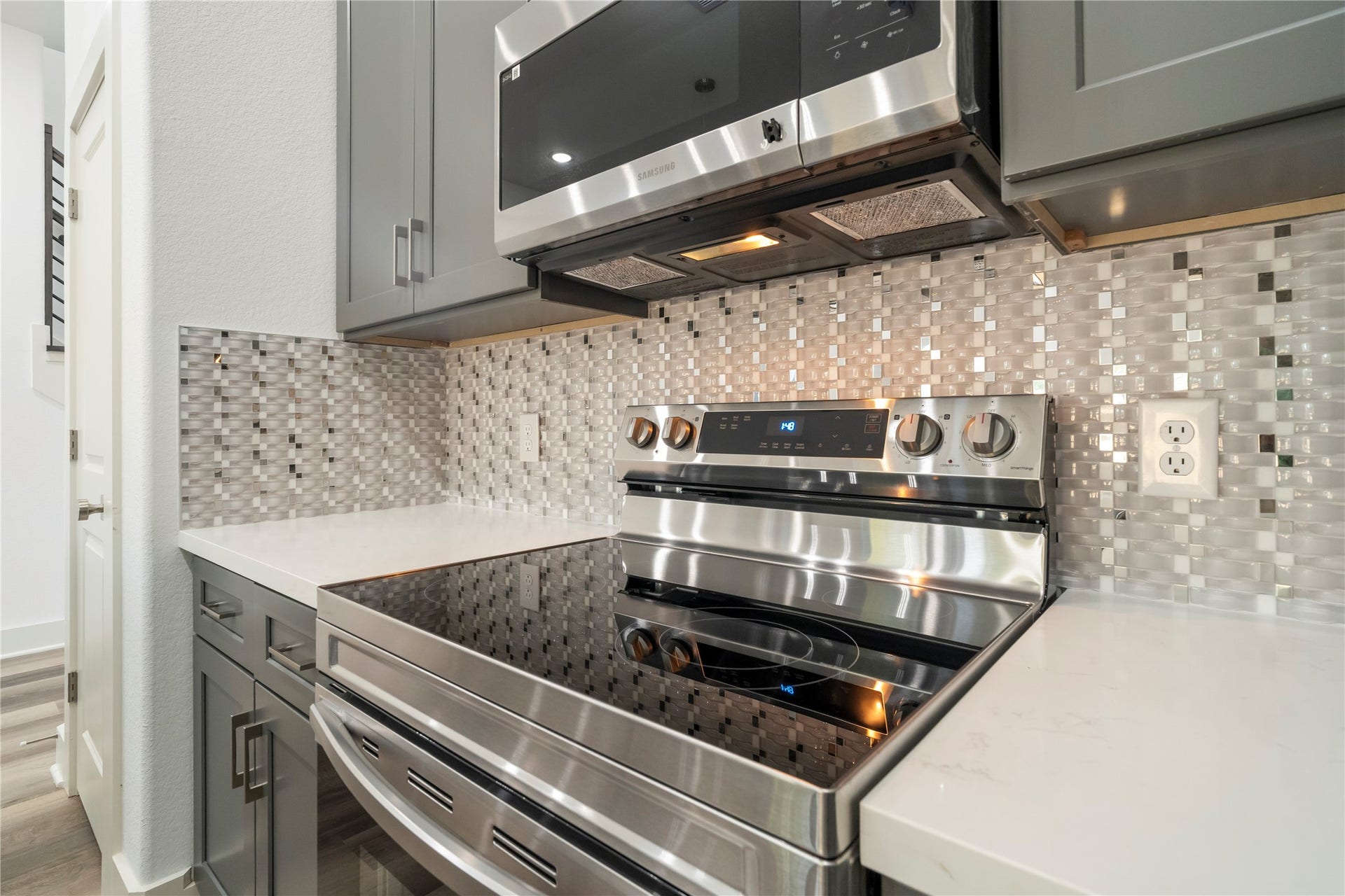 5629 Malmedy Road, Houston, TX 77033 Modern kitchen with sleek stainless steel appliances, elegant gray cabinetry, and a stylish mosaic tile backsplash.