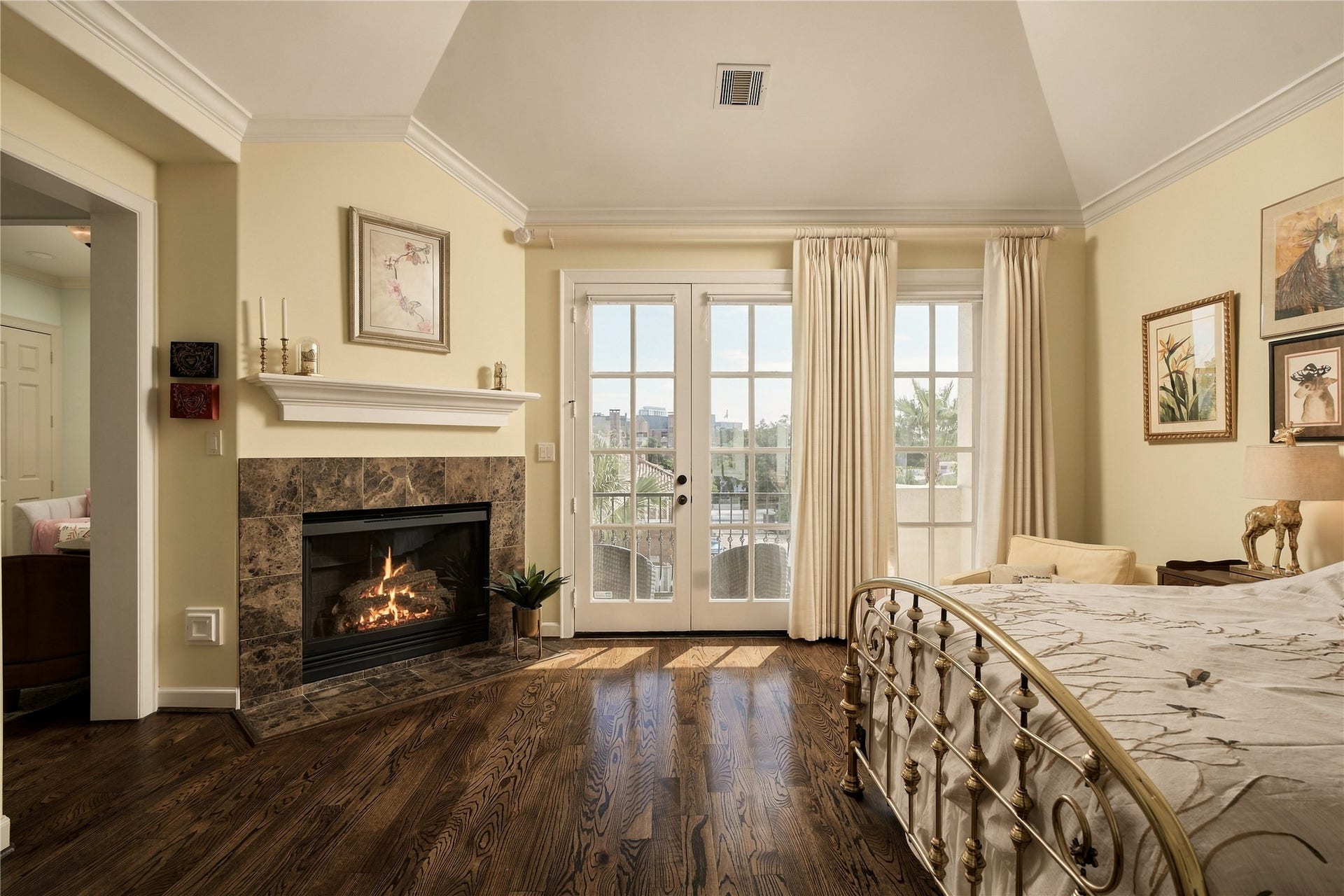 523 Lovett Boulevard, Houston, TX 77006 French doors connect the primary directly to its private balcony, while the fireplace brings a sense of warmth and intimacy to an otherwise expansive retreat.