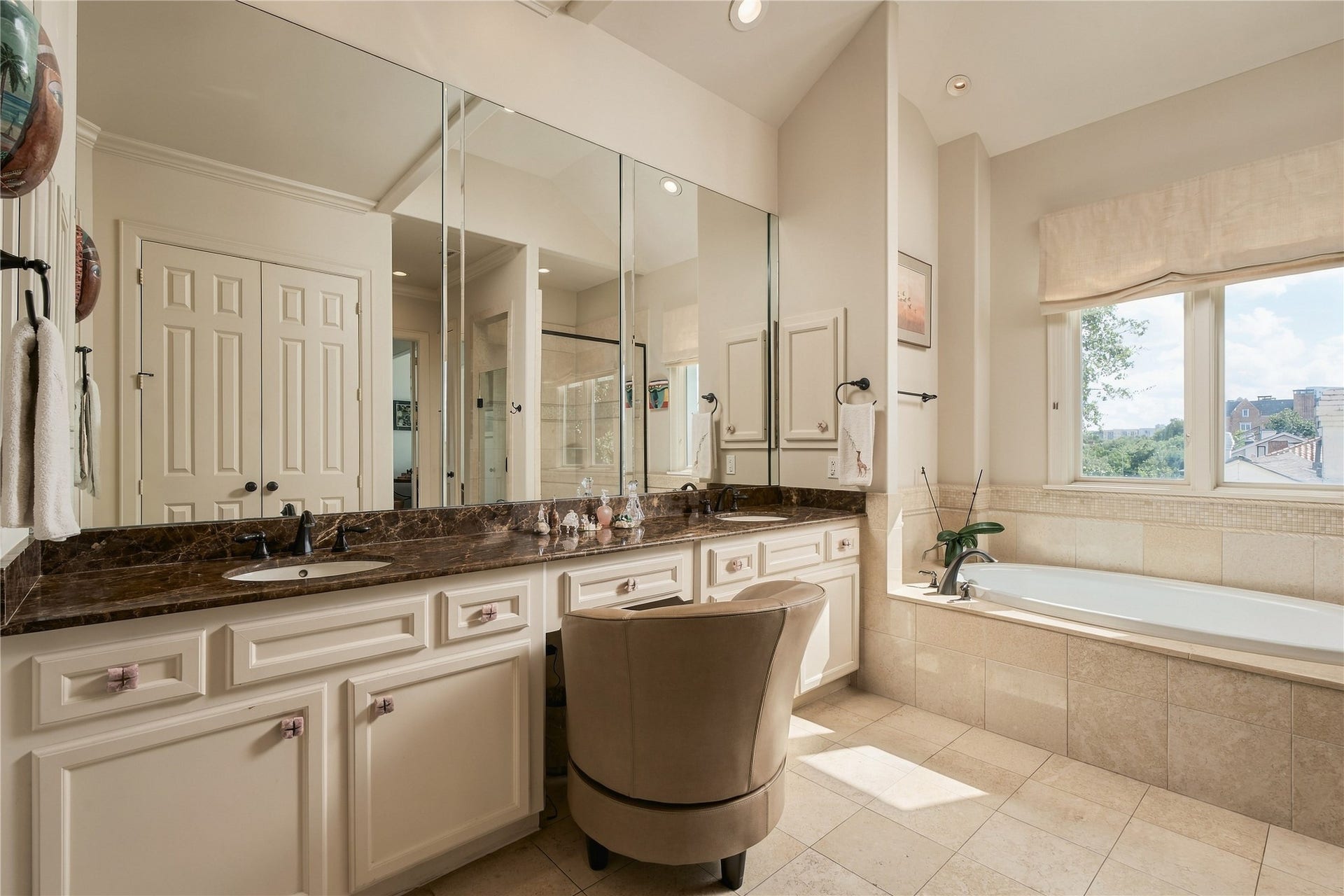 523 Lovett Boulevard, Houston, TX 77006 Natural light fills the primary bath, highlighting the expansive vanity, warm stone finishes and generous storage.