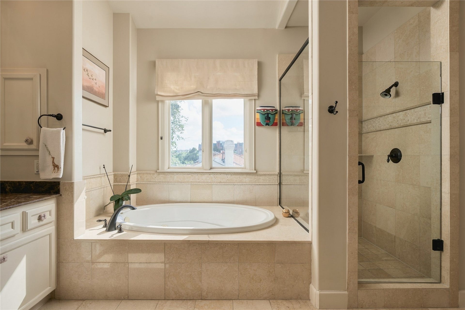 523 Lovett Boulevard, Houston, TX 77006 A jetted soaking tub and separate glass-enclosed shower create distinct spaces to slow down or get ready for the day, with natural light bringing warmth into the stone-finished bath.