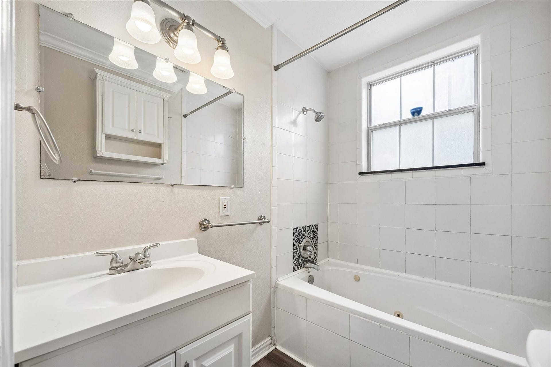 1020 Crocker Street, Houston, TX 77019 Bright bathroom featuring a clean, white vanity with ample storage, a large mirror with elegant lighting, and a relaxing bathtub with stylish tile accents.