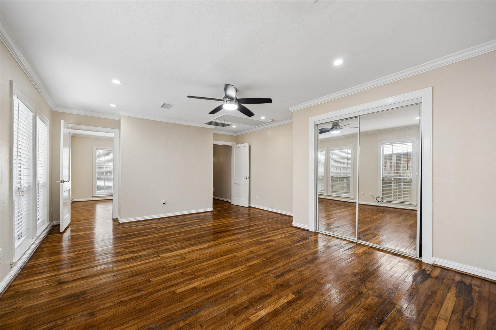 1020 Crocker Street, Houston, TX 77019 Spacious room with rich hardwood floors, a modern ceiling fan, and abundant natural light streaming through large windows and French doors.