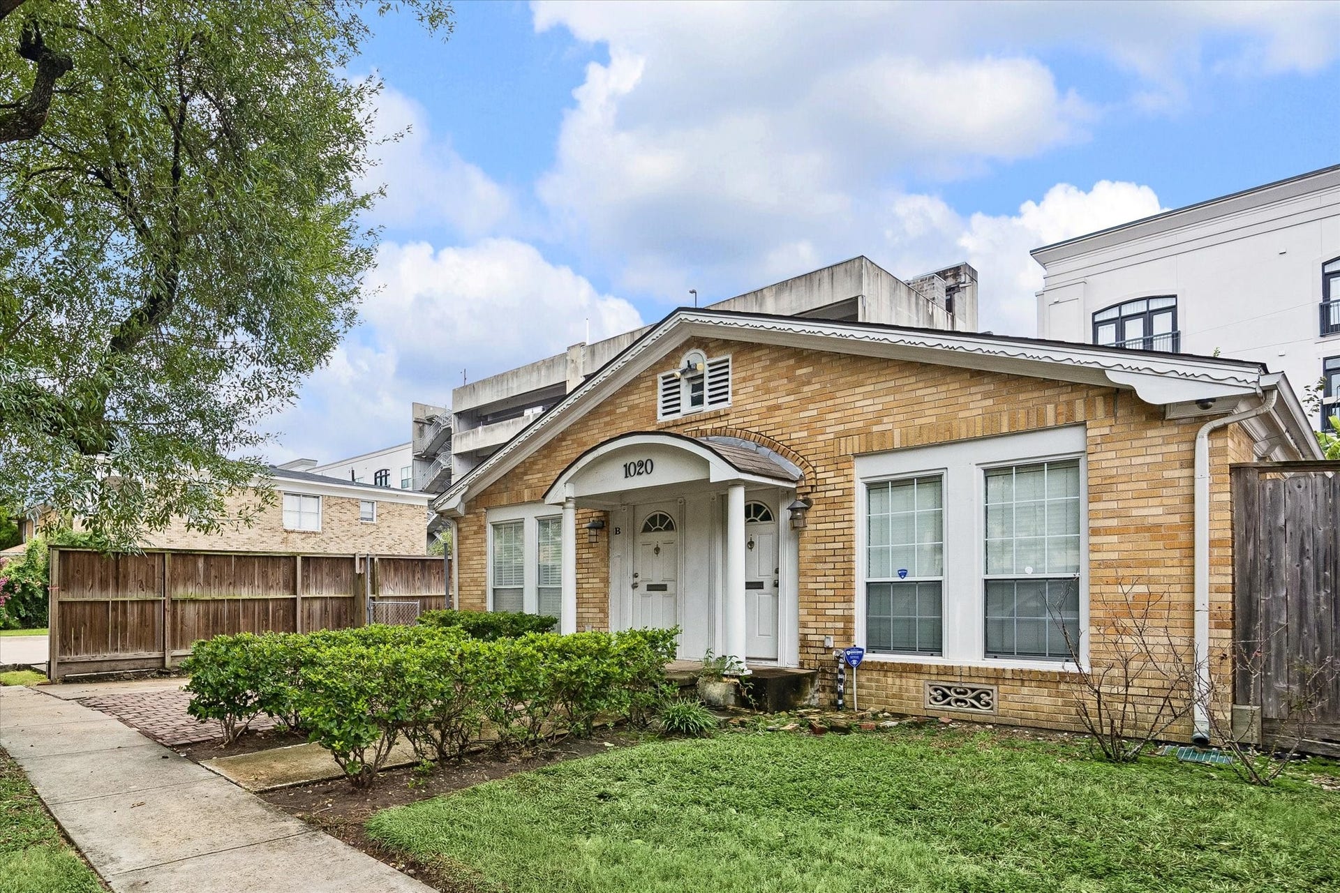 1020 Crocker Street, Houston, TX 77019 Charming single-story brick home with a welcoming front porch, lush landscaping, and a quaint garden area, all nestled in a serene neighborhood.
