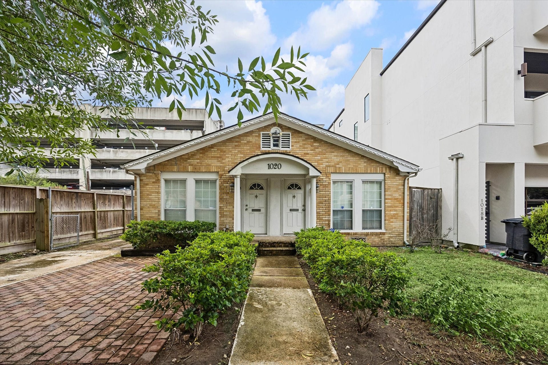 1020 Crocker Street, Houston, TX 77019 Charming single-story brick home featuring a welcoming double-door entrance, manicured shrubs, and a paved walkway.