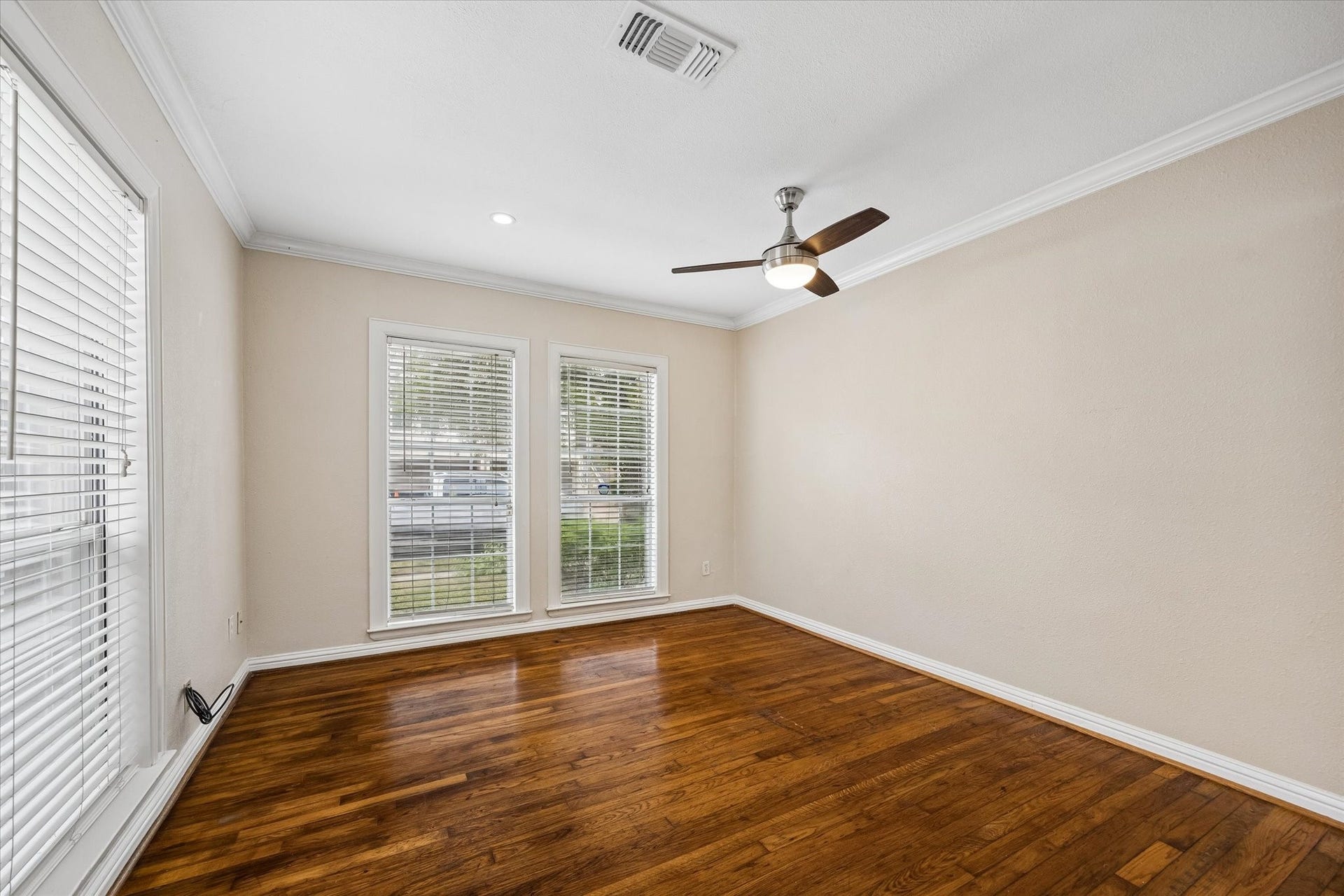 1020 Crocker Street, Houston, TX 77019 Bright and inviting room with rich wood flooring, large windows for natural light, and a modern ceiling fan.