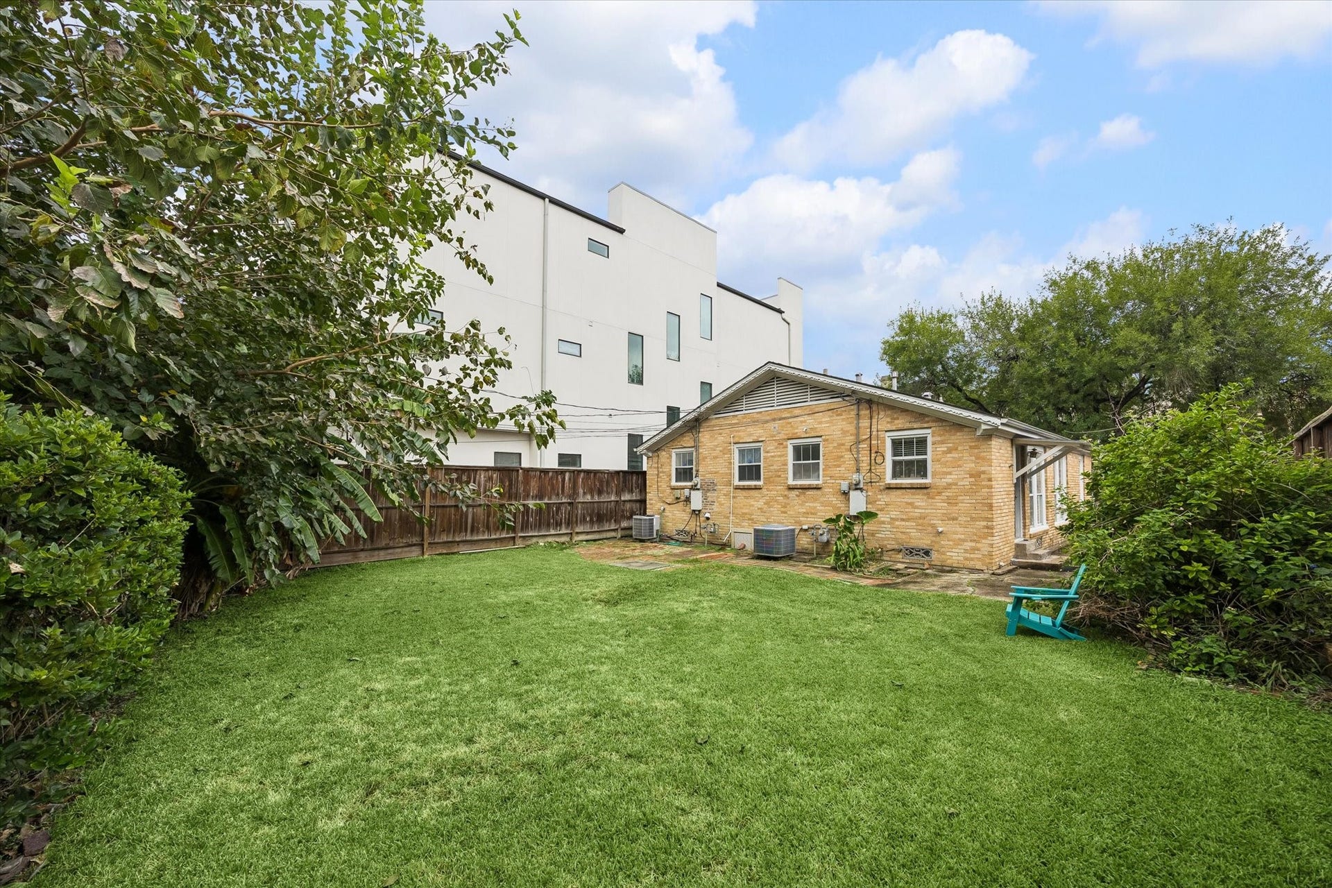 1020 Crocker Street, Houston, TX 77019 Charming backyard features lush greenery, a cozy brick house, and ample space for outdoor activities.