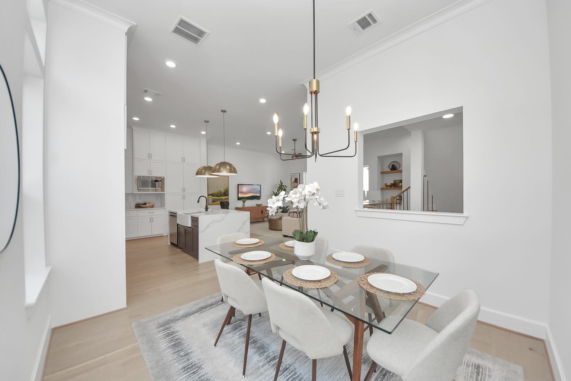927 Fisher Street, #B, Houston, TX 77018 Step into this modern, open-concept dining and kitchen area, where a glass dining table with elegant seating sits beneath a contemporary chandelier. The bright kitchen features white cabinetry, stainless steel appliances, and a farmhouse sink, while light wood flooring and stylish decor create an airy, welcoming atmosphere perfect for entertaining or daily living.