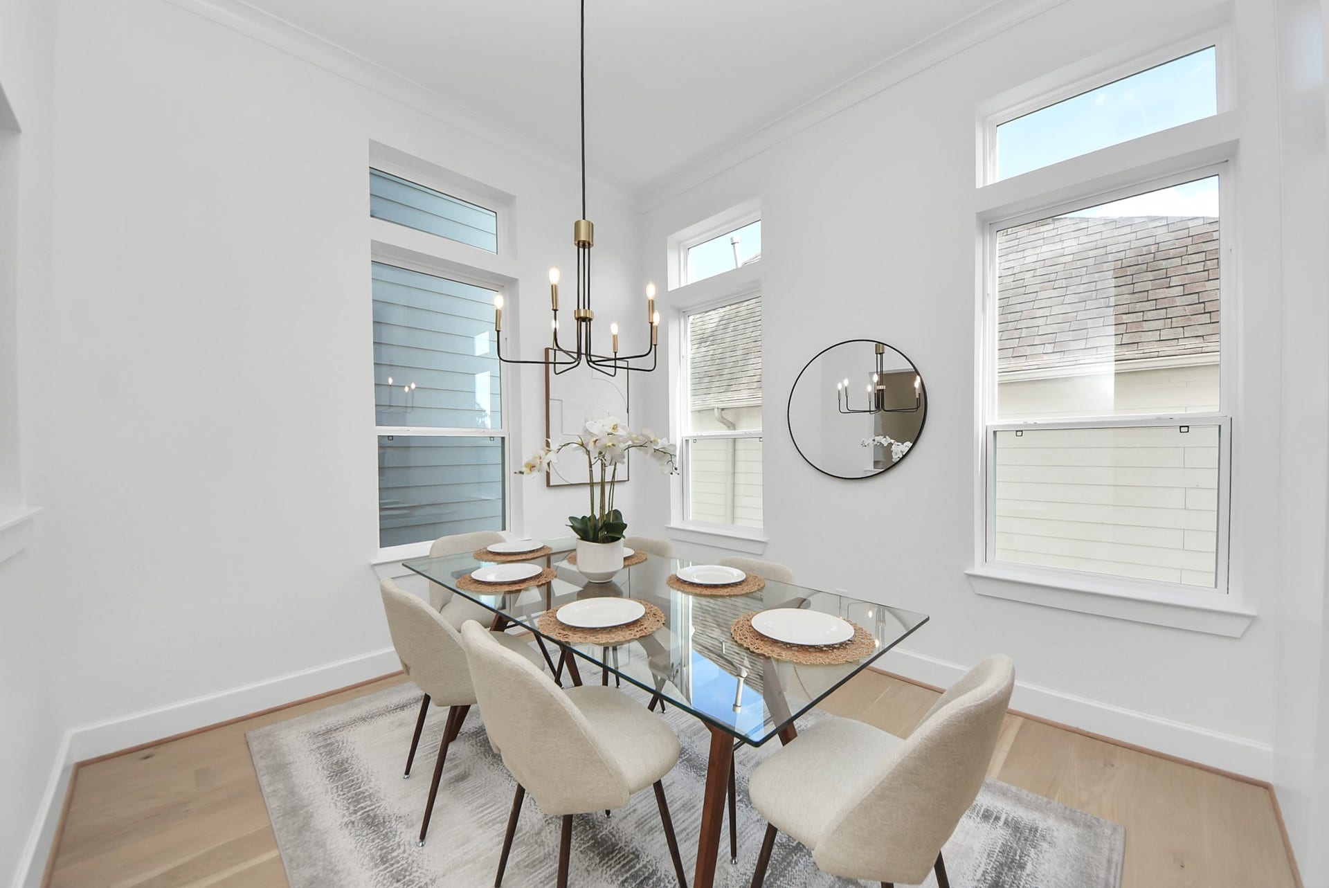 927 Fisher Street, #B, Houston, TX 77018 Step into this bright dining space with high ceilings and large windows, where modern decor complements a glass-top table with six upholstered chairs. A contemporary chandelier and decorative mirror add elegance, making this area both inviting and sophisticated.
