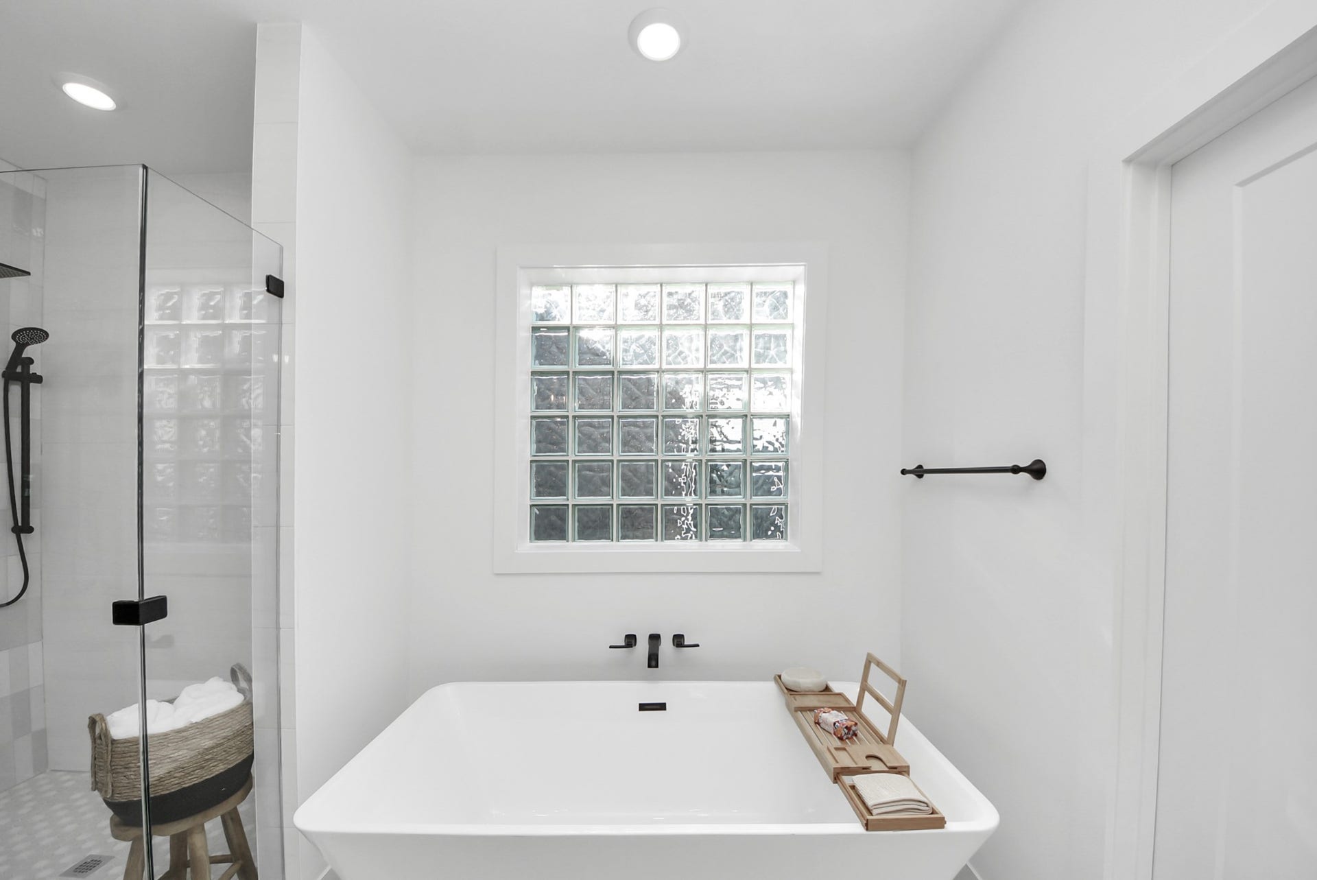 927 Fisher Street, #B, Houston, TX 77018 Relax in this minimalist bathroom, complete with a freestanding tub, glass-enclosed shower, and a large frosted window for natural light. Black fixtures contrast the clean white finishes, creating a modern, spa-like retreat.