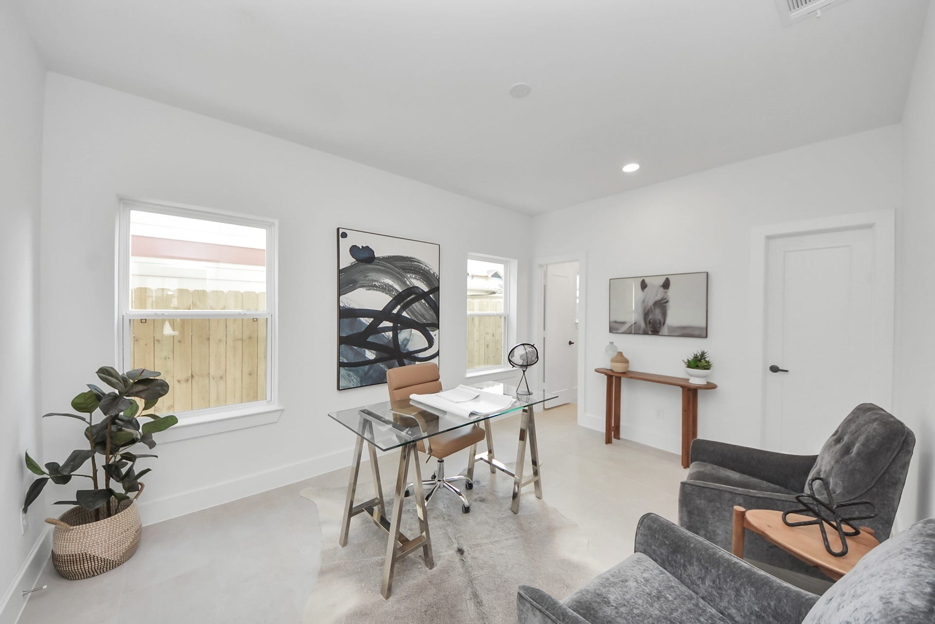 927 Fisher Street, #B, Houston, TX 77018 Step into this bright, modern home office, where a glass desk and comfortable seating are complemented by stylish artwork and minimalistic decor. Large windows fill the space with natural light, while neutral walls create an inviting and functional environment perfect for focused work or study.